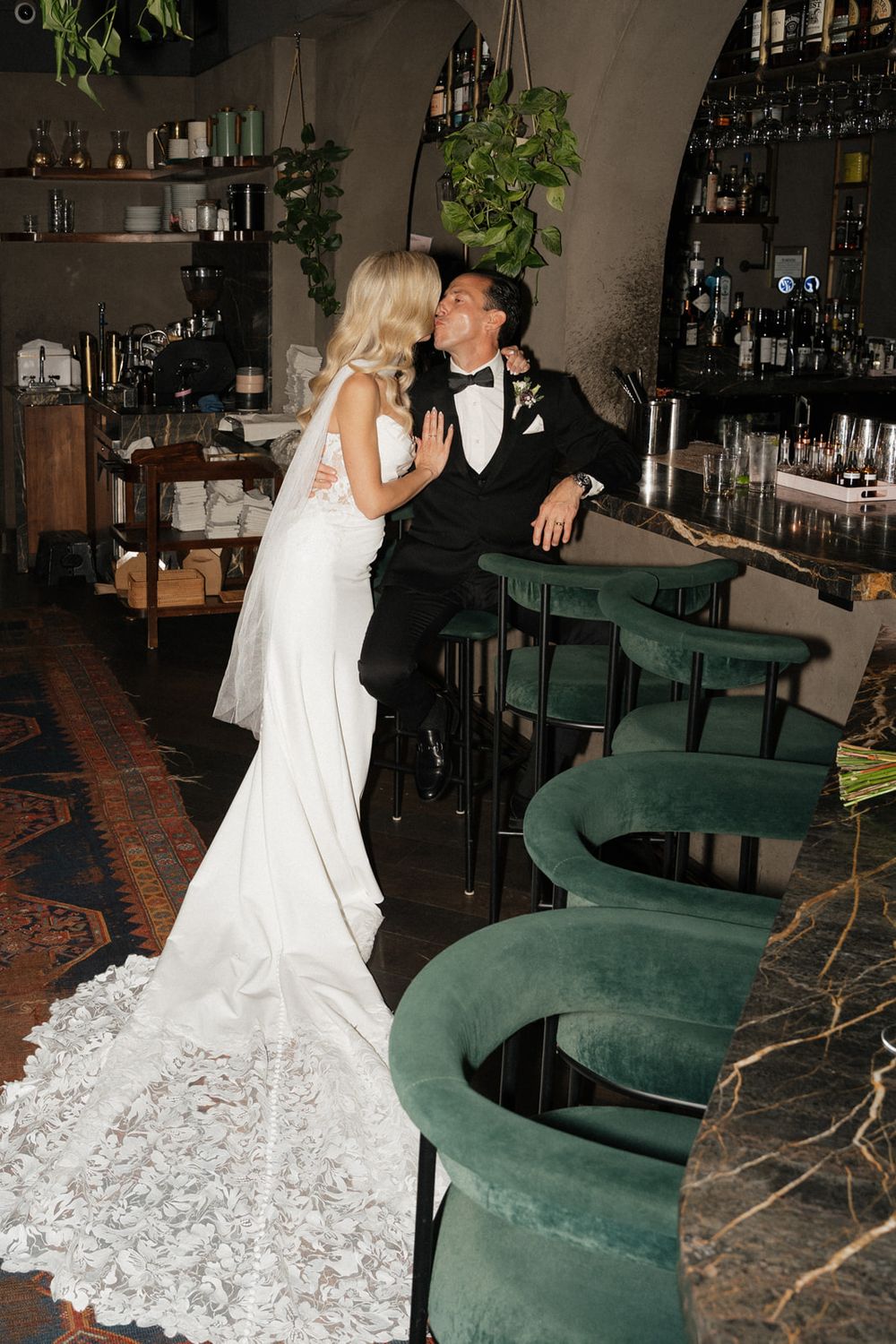 Couple dancing in a bar with emerald green velvet seating and dark wood decor.