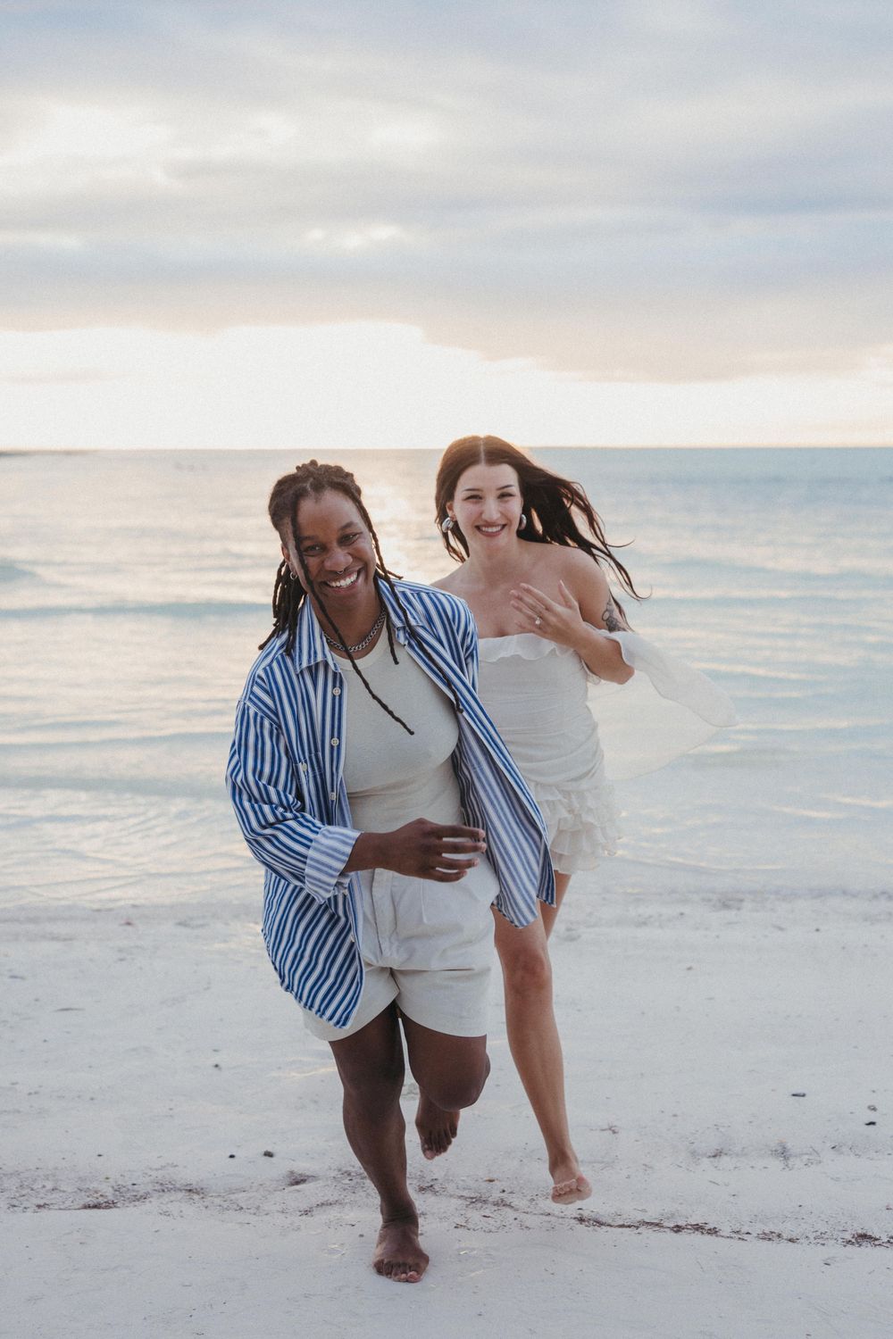 A gay couple running hand in hand along the beach in Holbox just after their surprise proposal at sunset.