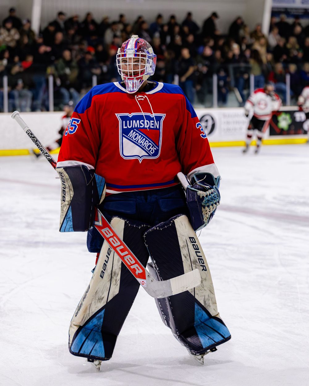 Lumsden Monarchs goalie number 35 in red CCM gear stands ready on the ice during a hockey game.