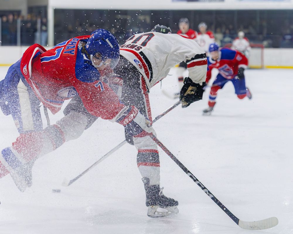 Lumsden Monarchs player battles opponent in intense ice hockey collision during a competitive league game.