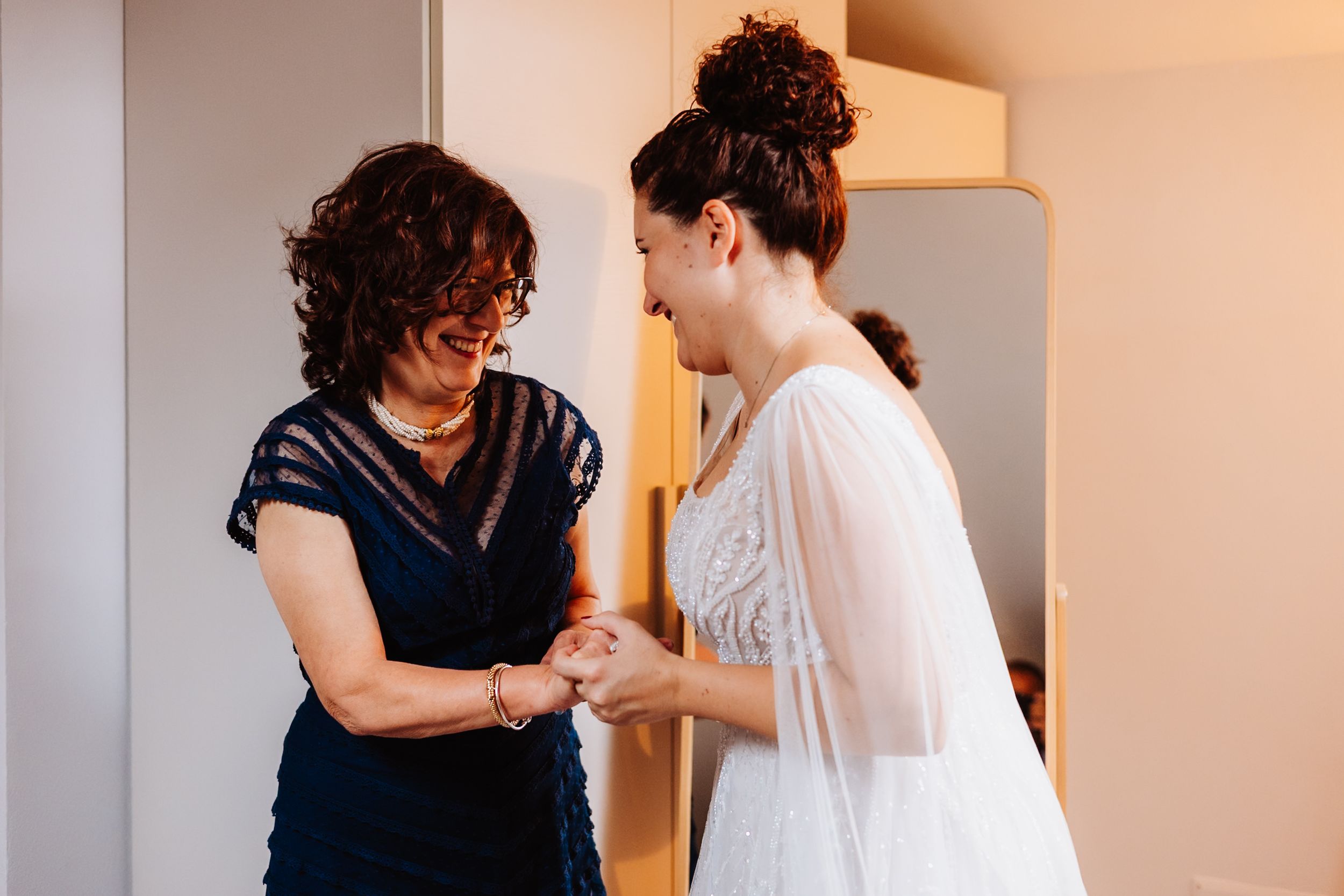 Two dancers practicing together in a studio with warm lighting and white walls.