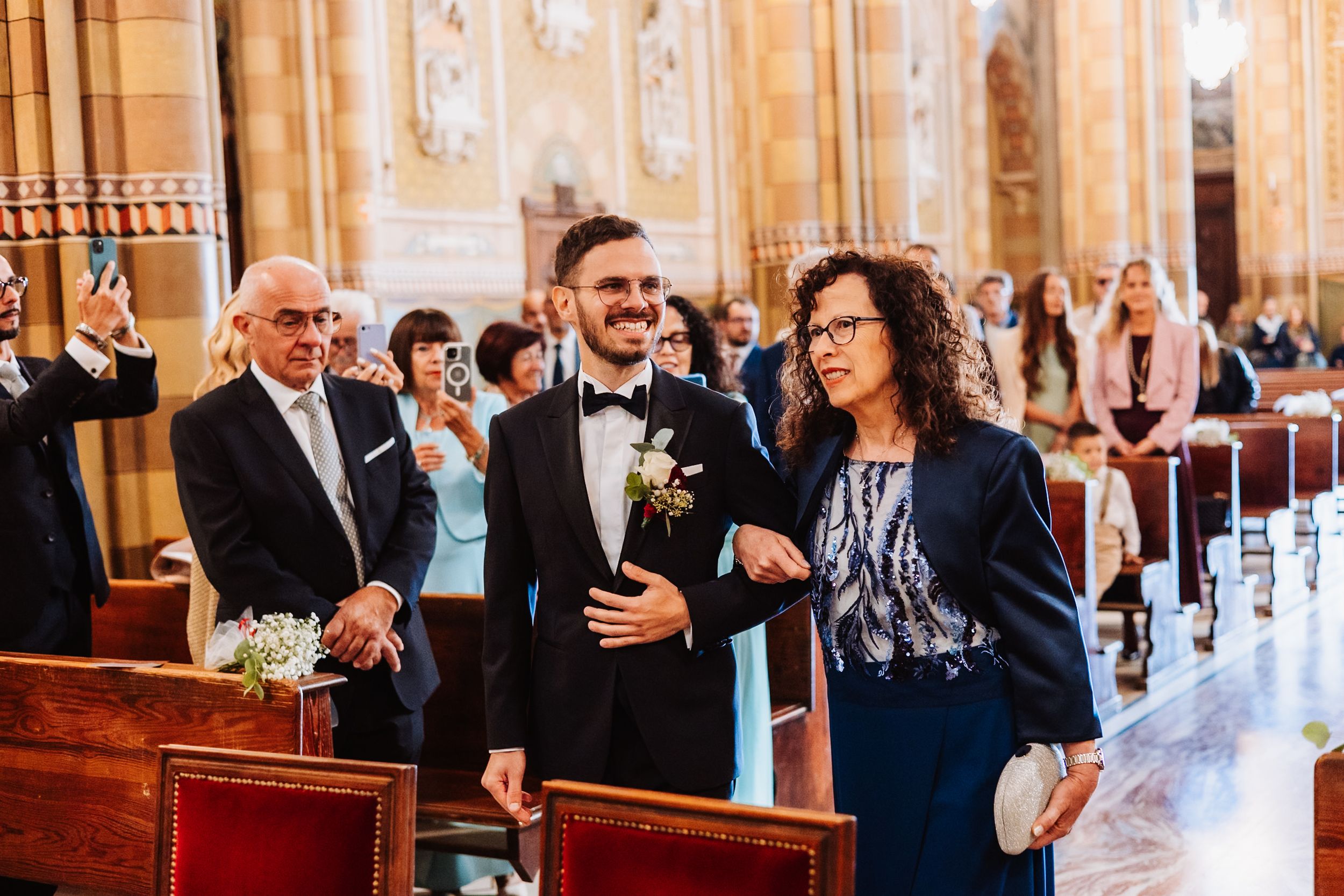 Wedding guests celebrate and toast during an elegant reception in a grand wood-paneled ballroom.