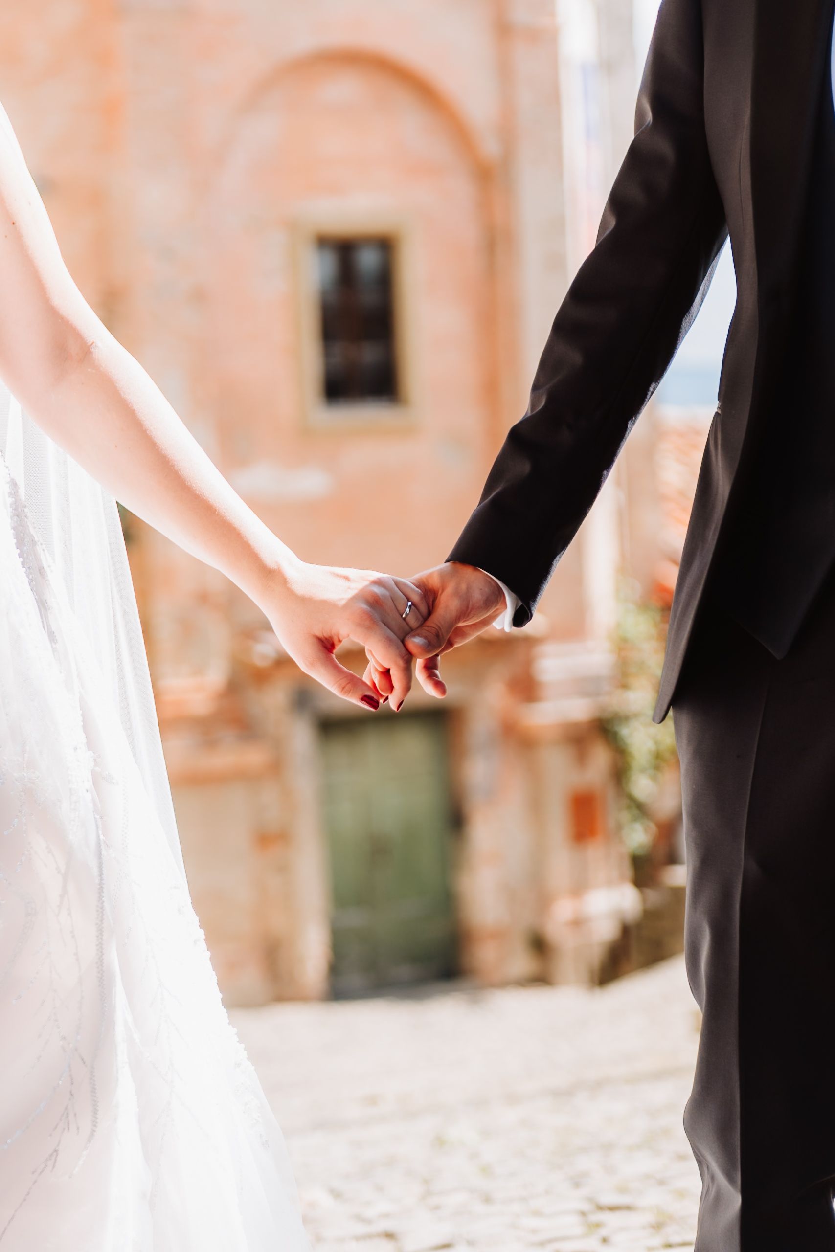 Close-up view of bride and groom holding hands during romantic outdoor wedding ceremony.