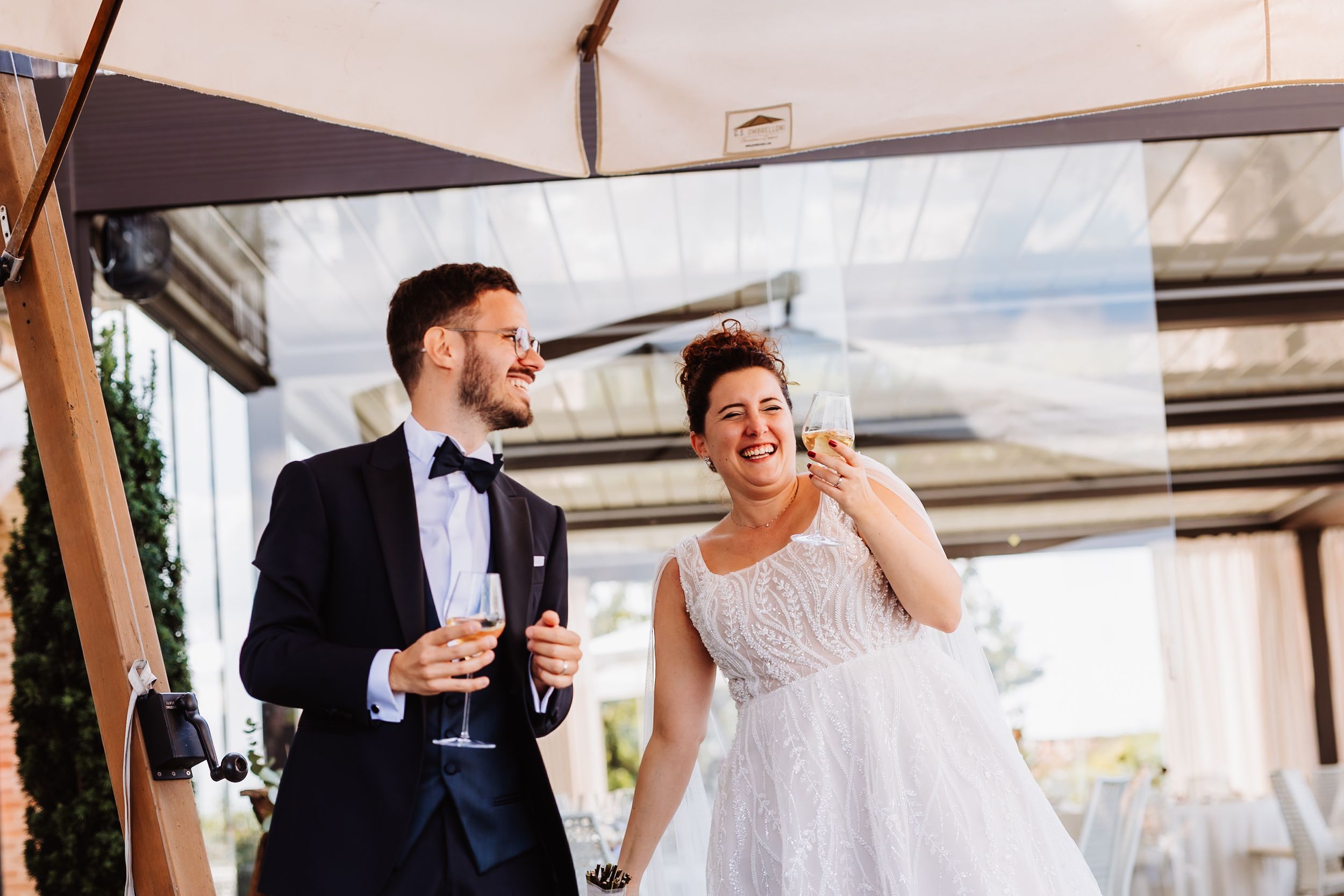 A couple shares a romantic moment together at an outdoor wedding reception under a white tent.