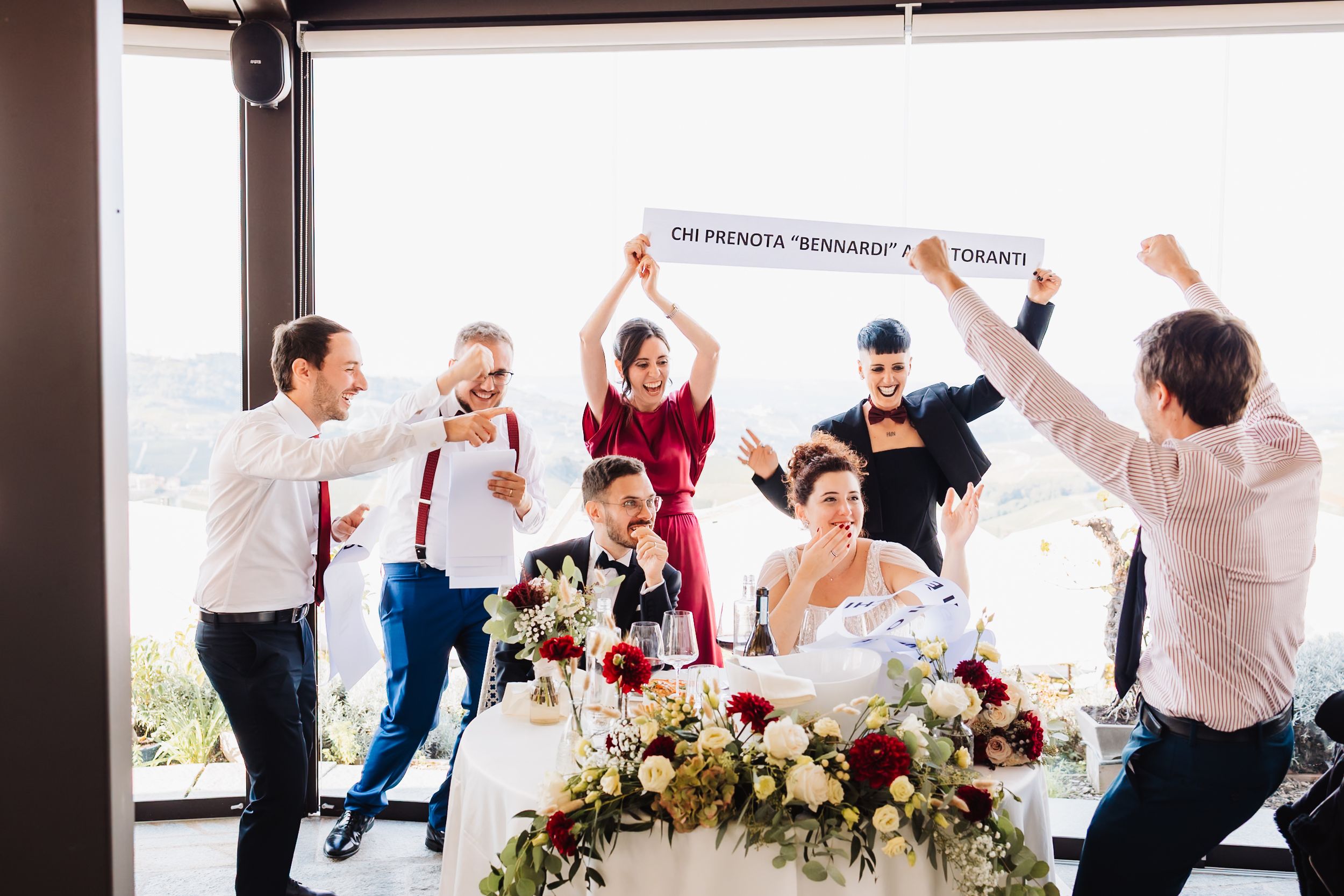 Wedding guests cheering and raising their arms in celebration during a joyful reception moment.