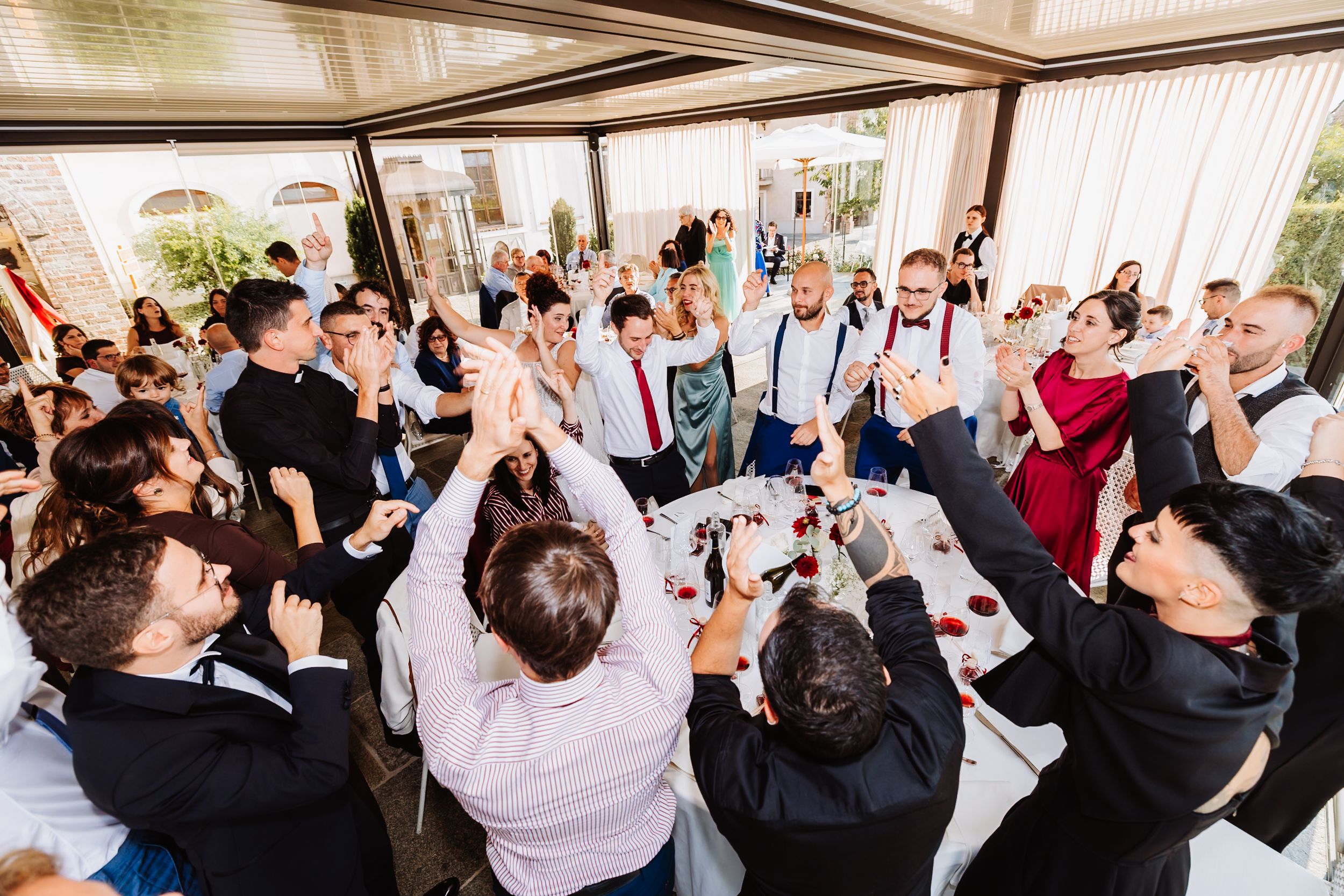 Wedding guests dancing and celebrating together during a lively reception party at an indoor venue.
