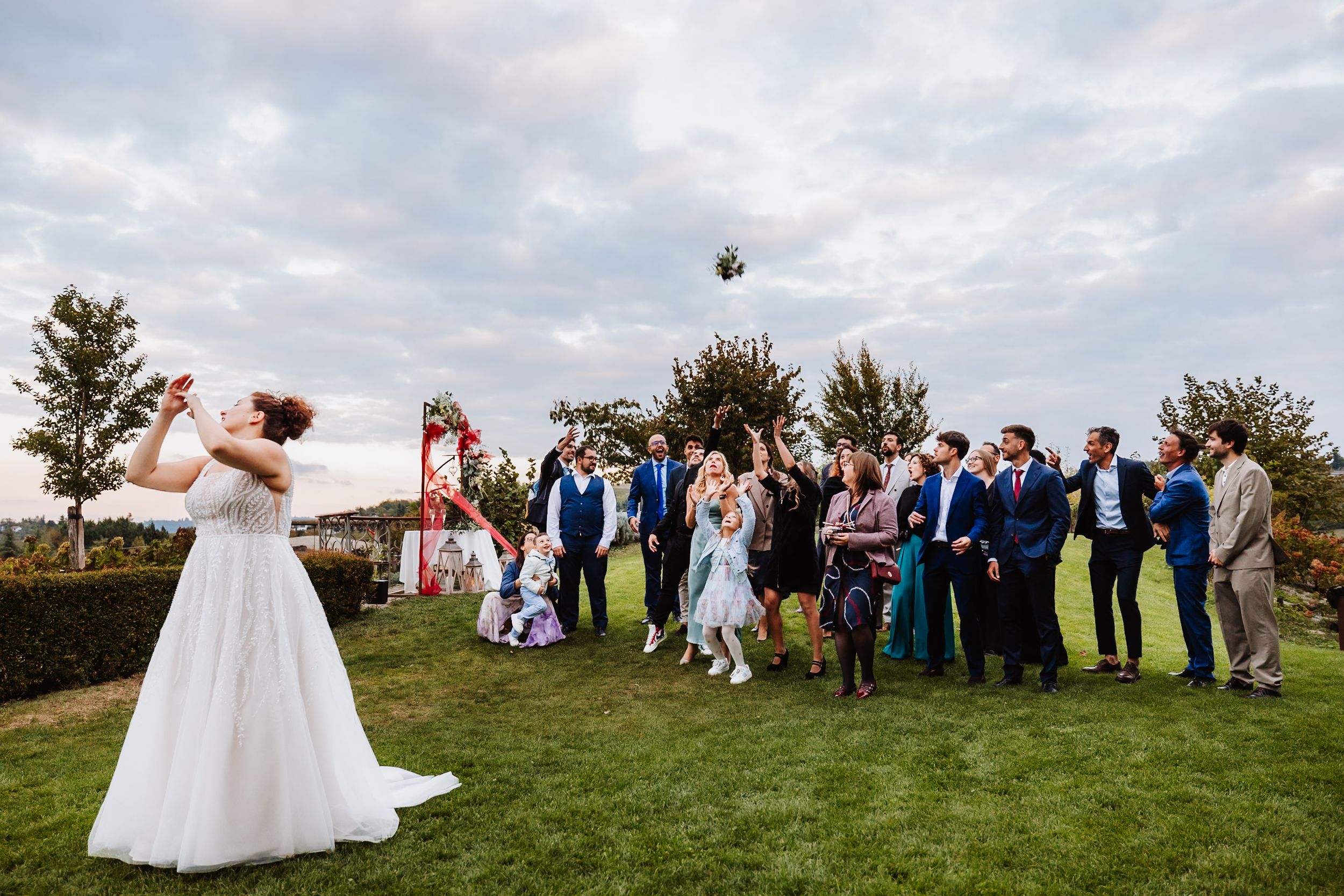 A panoramic sequence of wedding guests tossing flower petals during an outdoor celebration on a hilltop.