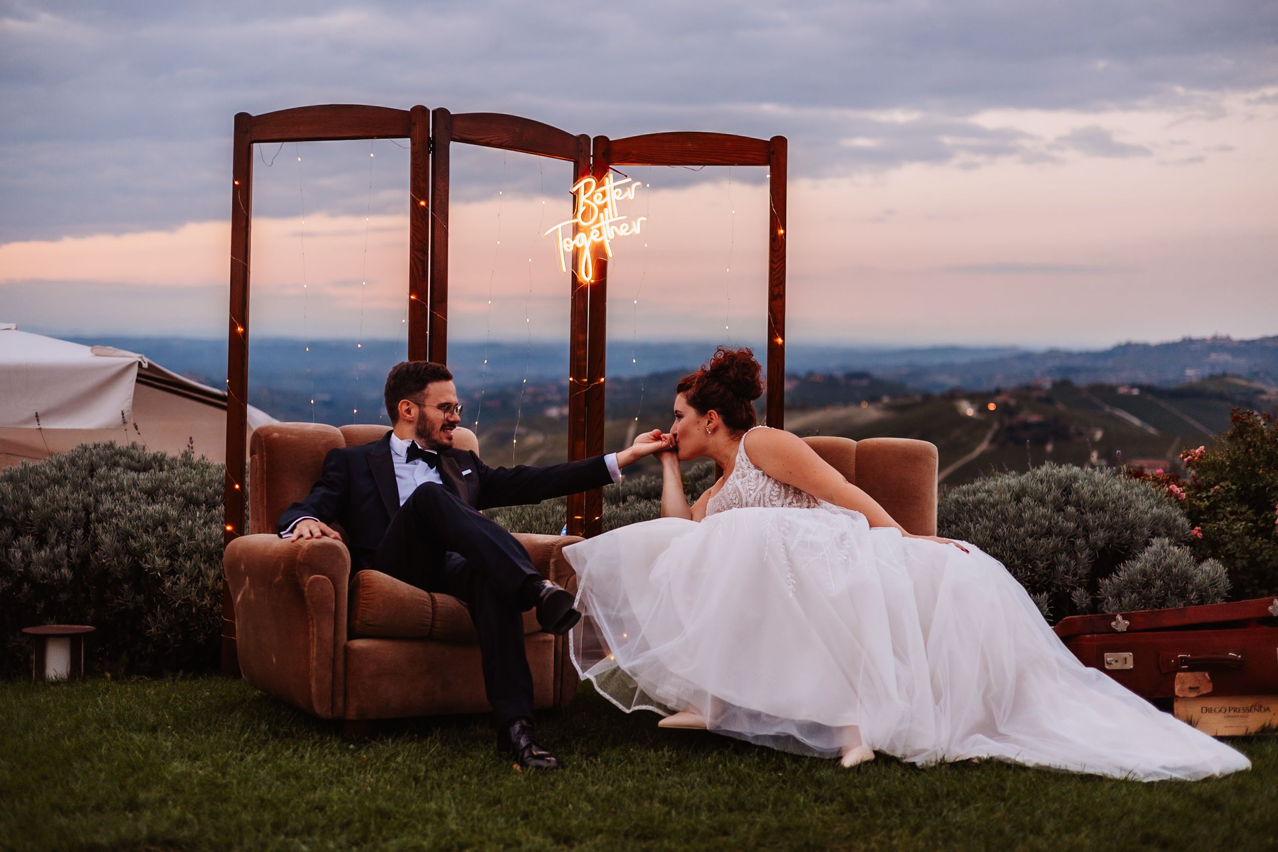 Romantic sunset wedding photos taken under wooden pergolas at a scenic outdoor venue with mountain views.