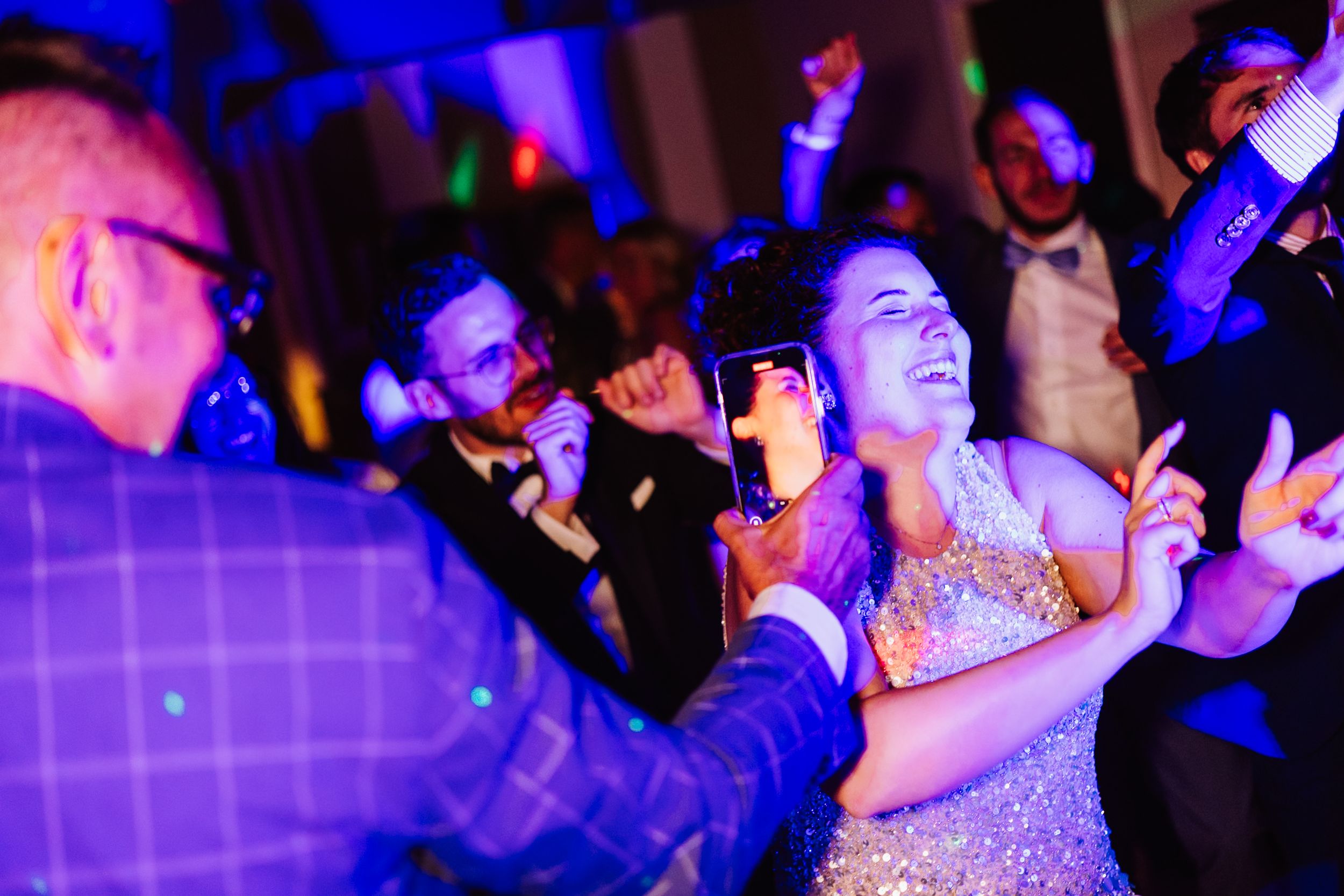 People dancing and enjoying themselves at a nightclub with blue and purple lighting effects.