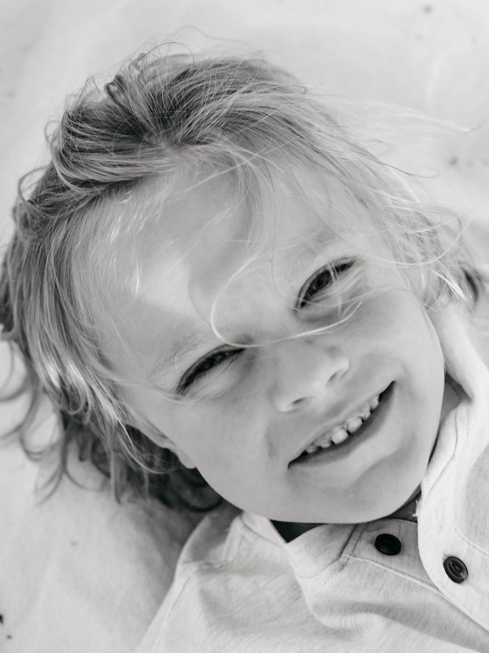 A series of black and white close-up portraits showing joyful expressions and windswept hair against a light background.