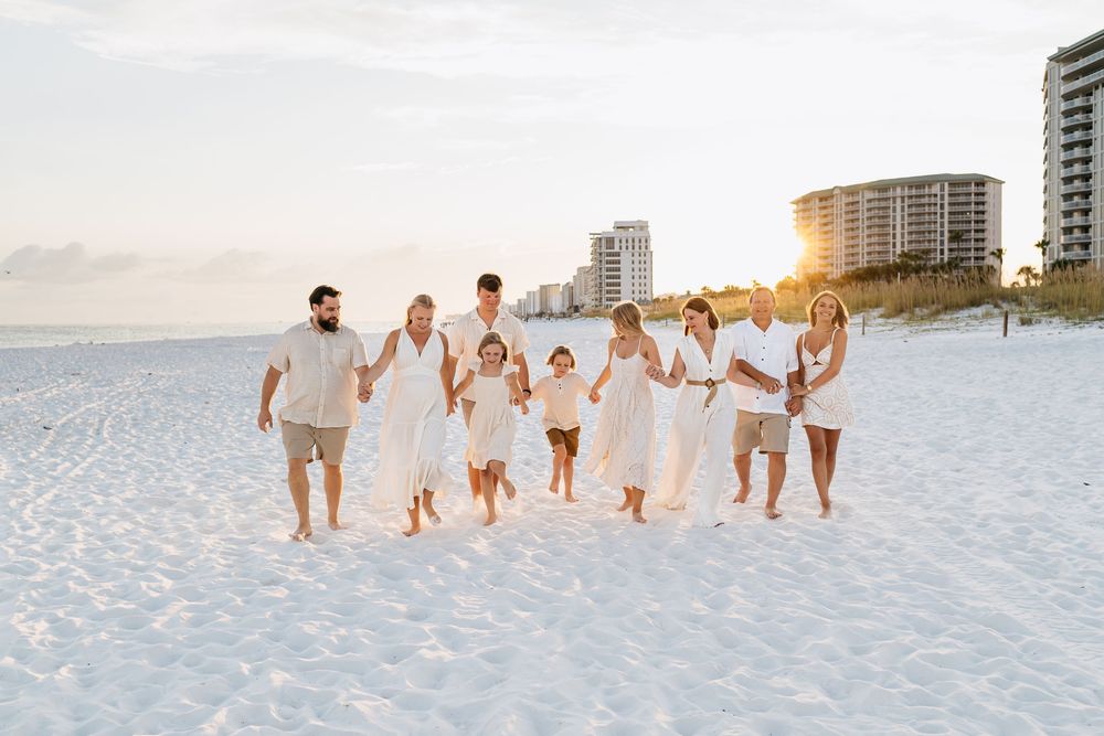 Group walking together along pristine white sandy beach at sunset creating footprints in the sand.