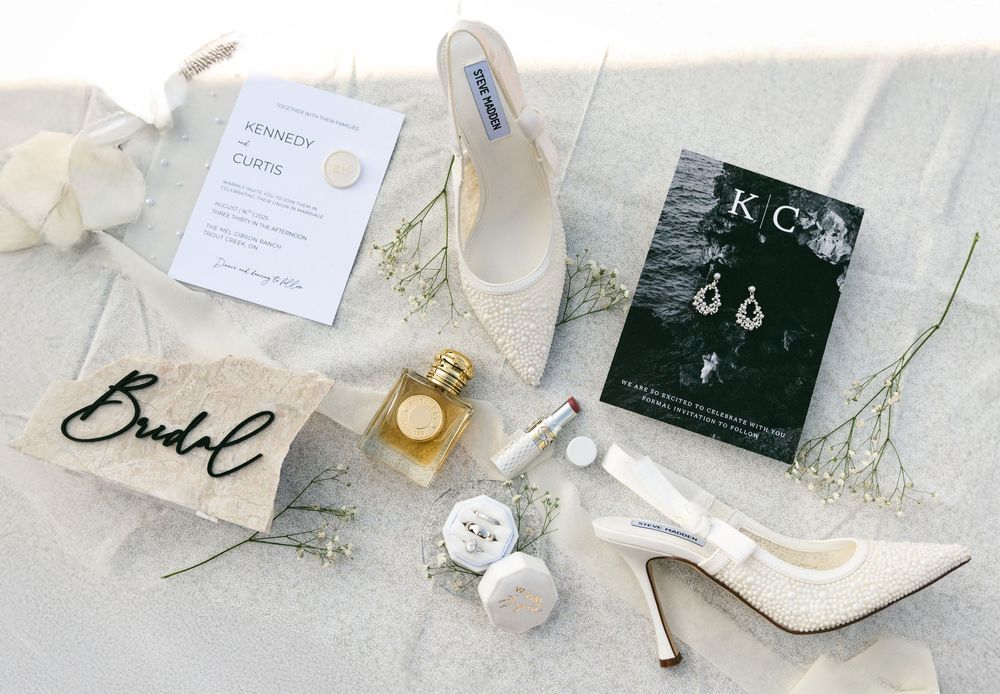 Elegant wedding accessories and jewelry laid out on a light gray surface with delicate floral accents.