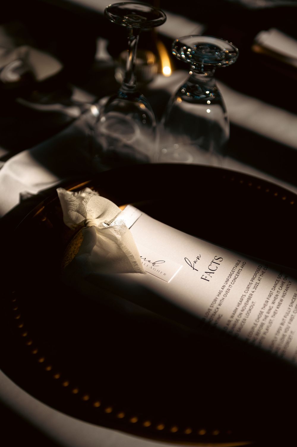 Wedding menu cards and place settings arranged on a dark table with dramatic lighting.