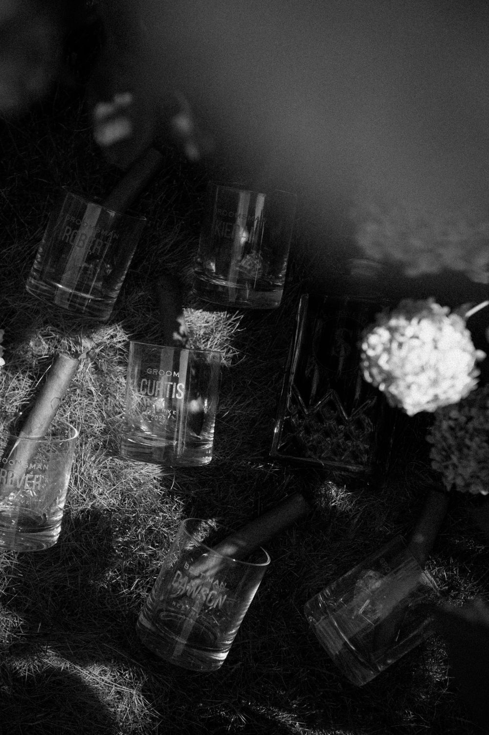 Dark and dramatic arrangement of glass bottles with white floral accents.