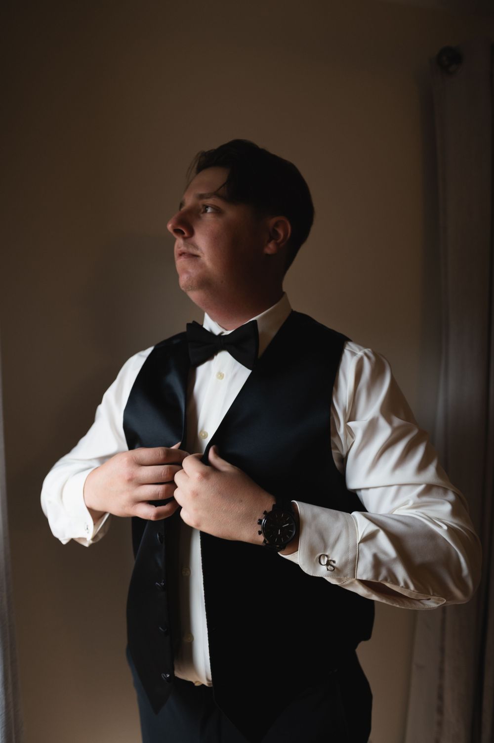 Close-up shots of someone adjusting a black vest over a white dress shirt in dramatic lighting.