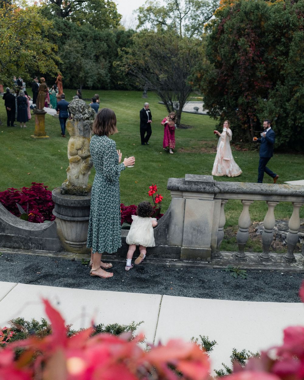 A mother and child wave to other guests in the garden at a Cuneo Mansion Wedding reception.