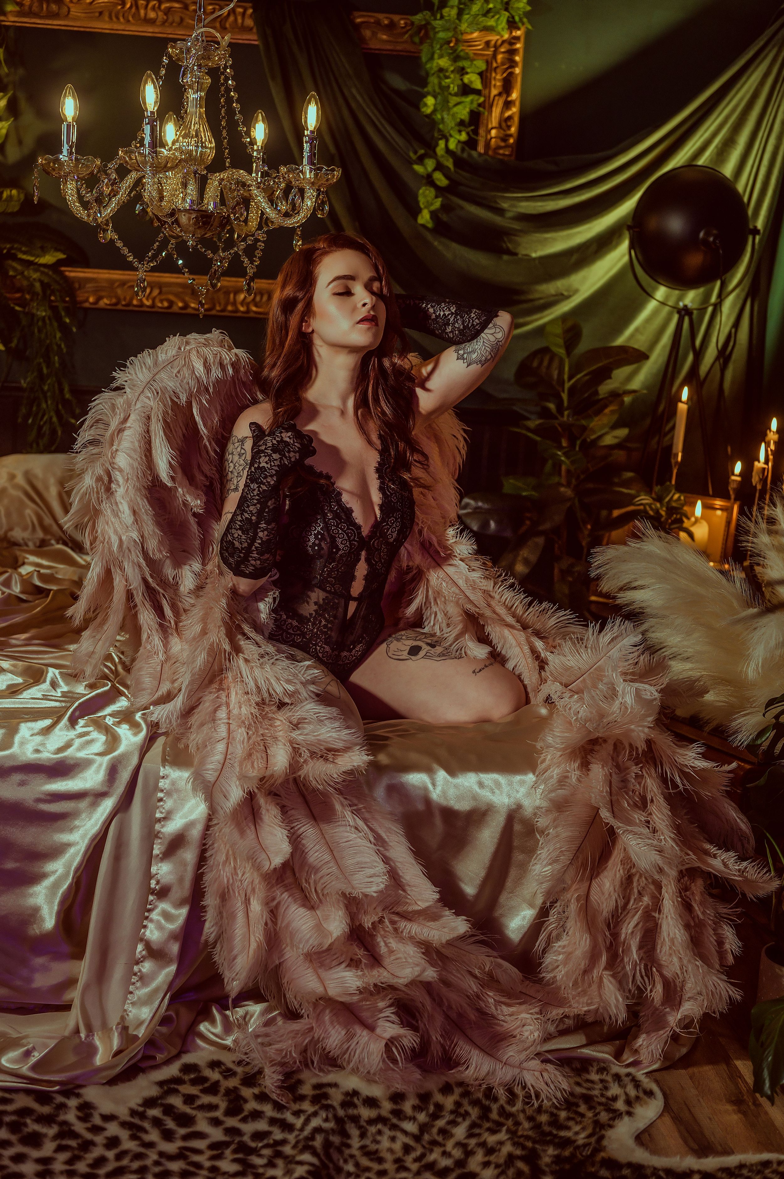 Glamour portrait with crystal chandelier, flowing feather robe and dramatic vintage decor.