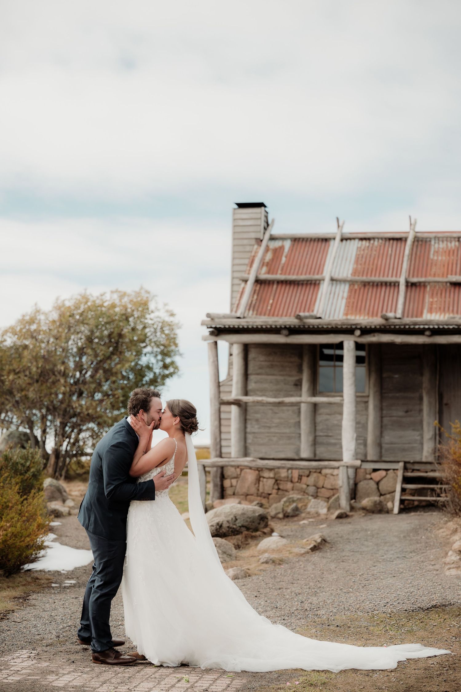 Rustic wooden barn serves as backdrop for romantic wedding portraits in Australian countryside.