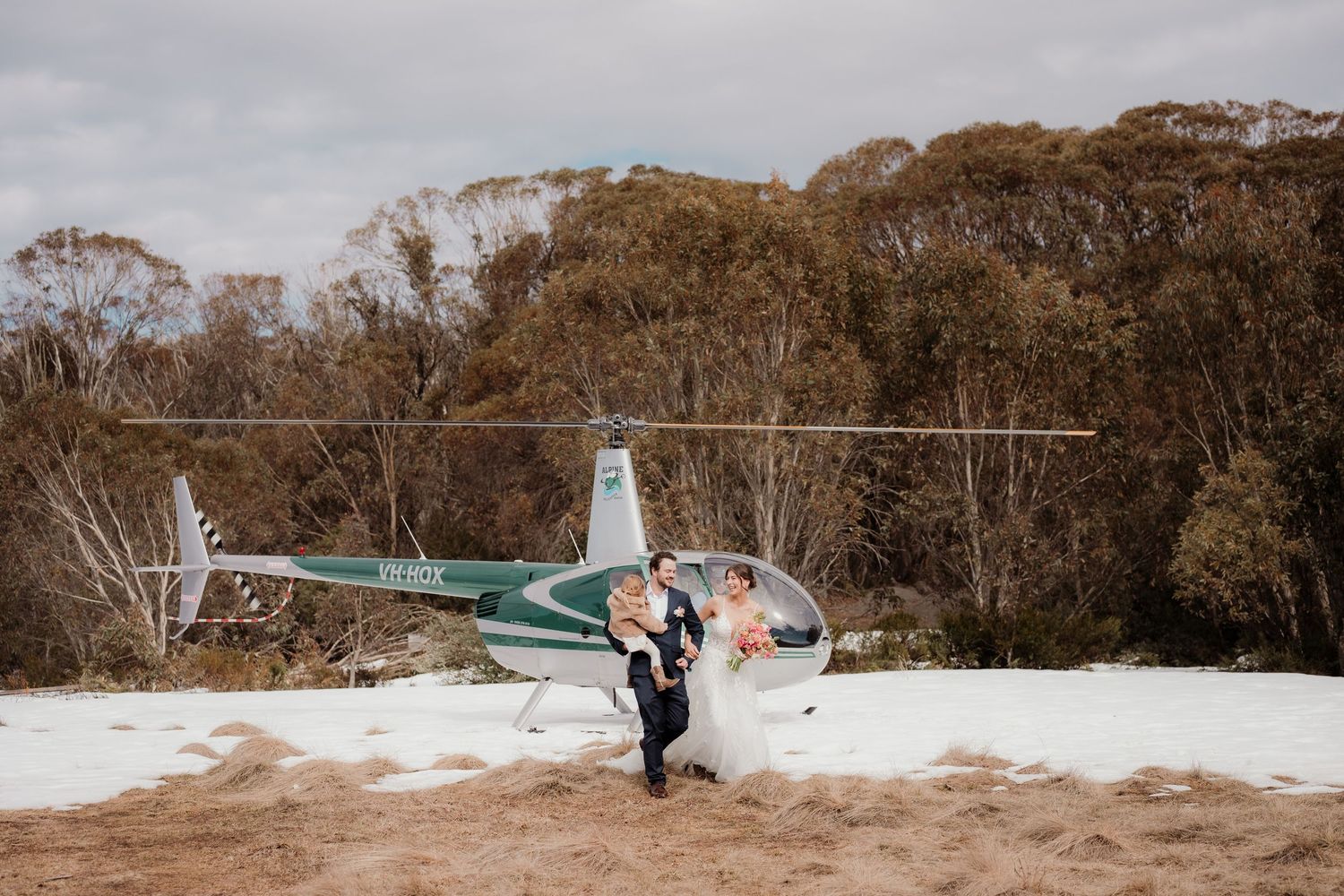 A small aircraft lies damaged in snowy terrain with emergency responders assessing the crash scene.