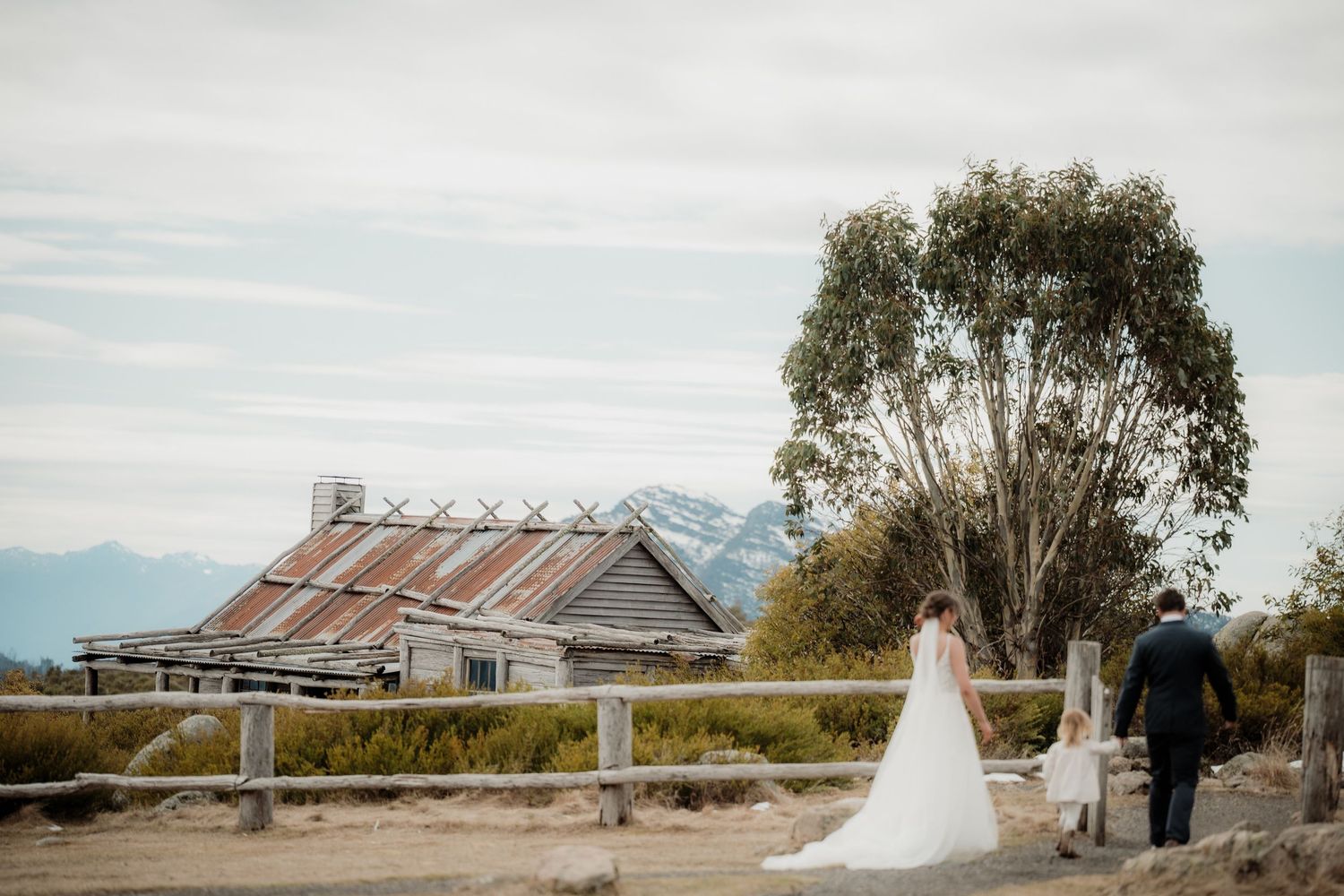 A panoramic view of a mountain landscape with a rustic barn and wedding ceremony setup in the foreground.