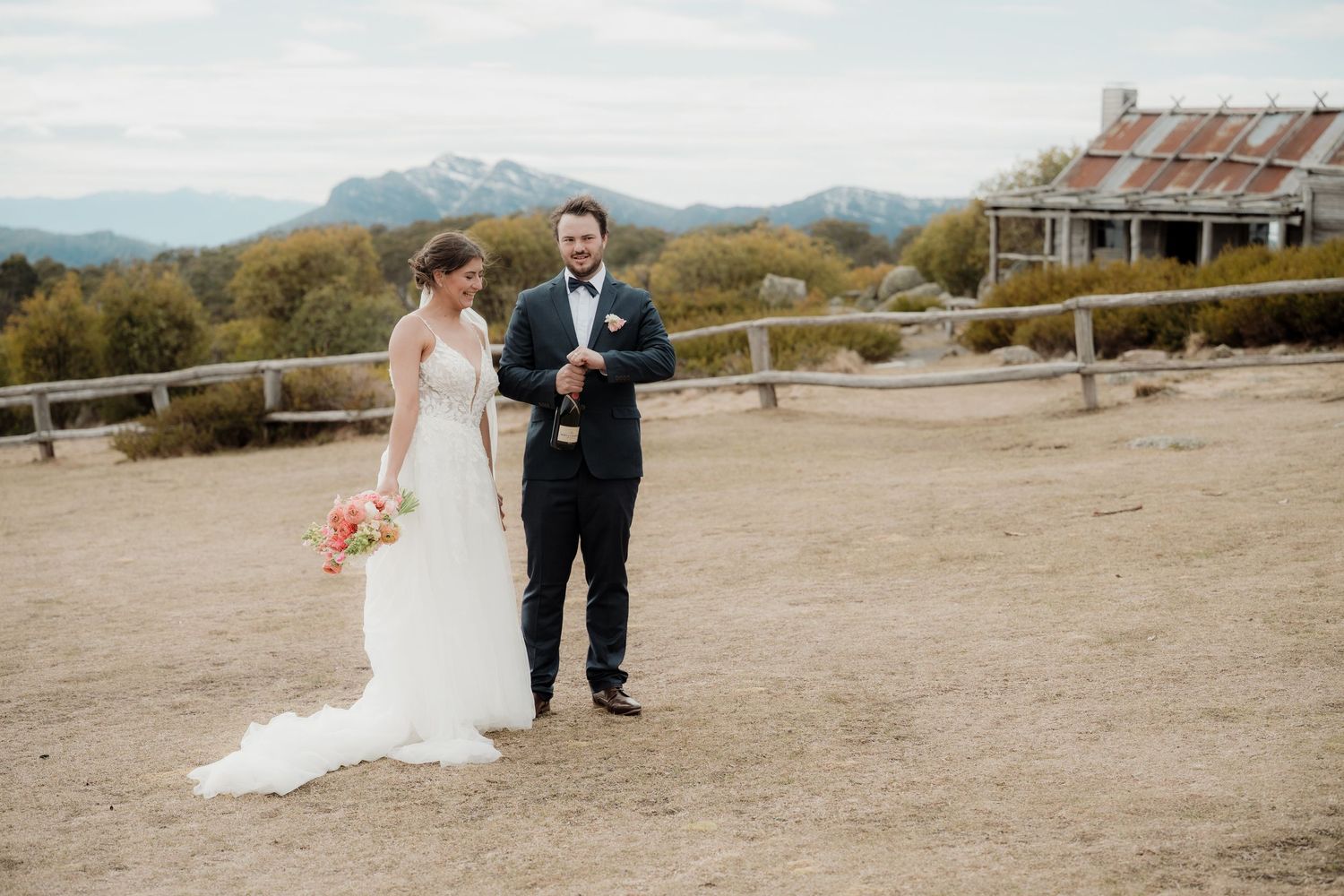 A couple walks together on a desert path with mountains in the background during a wedding photo session.