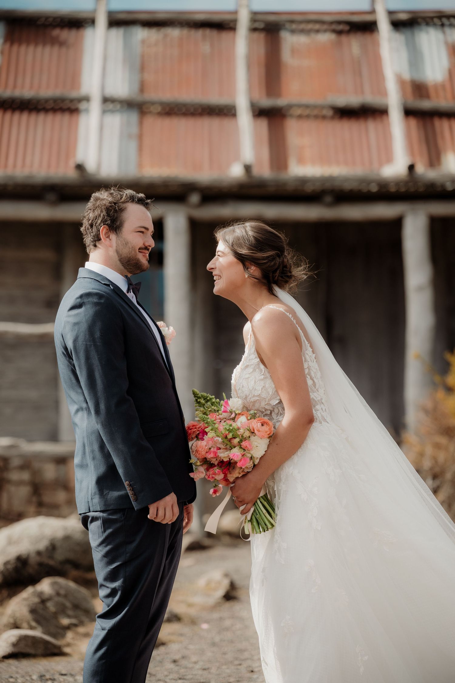 Bride and groom share intimate moments during their first look photo session on a rustic industrial backdrop.