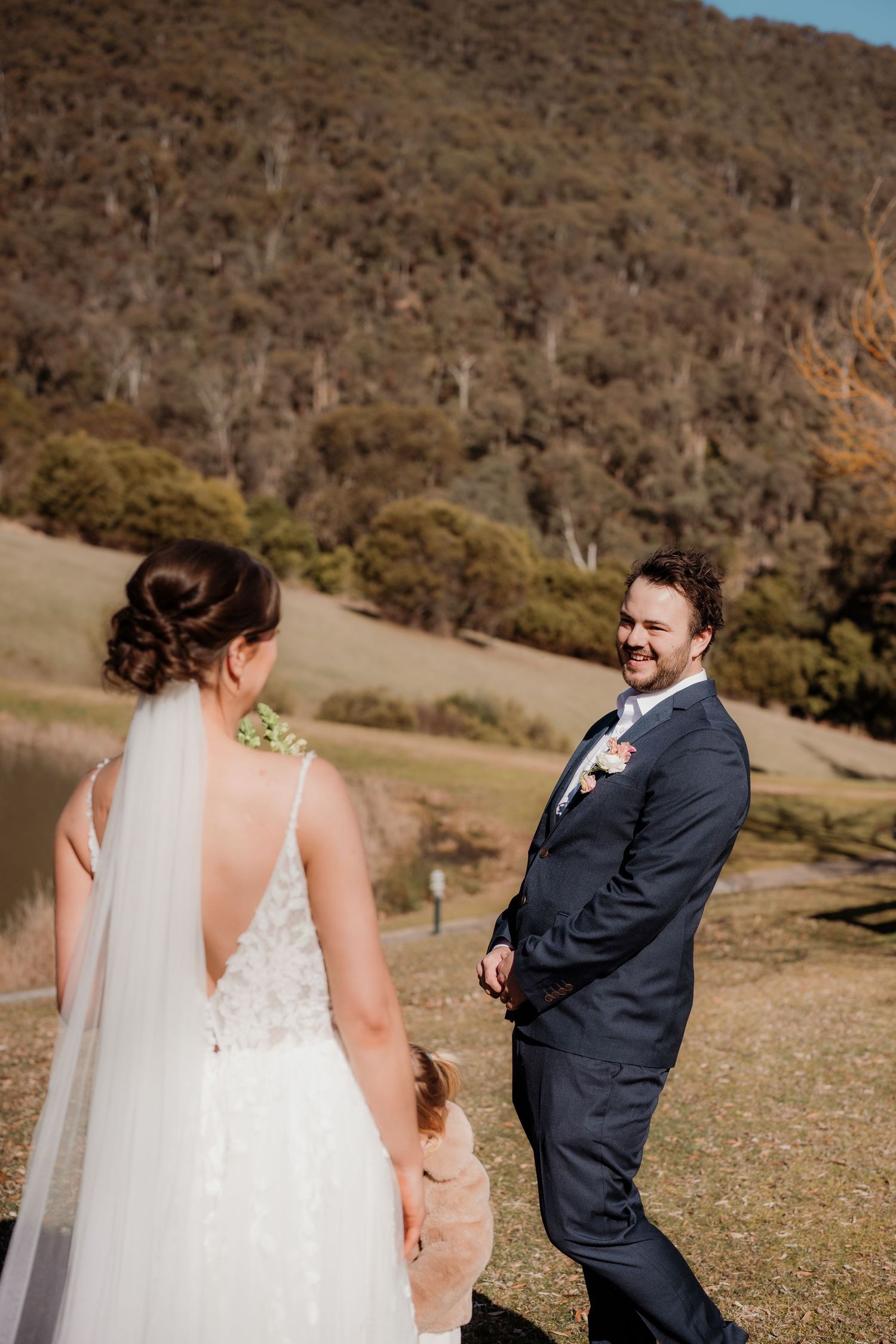 A couple shares a playful moment during their wedding photoshoot in a scenic mountainous landscape.