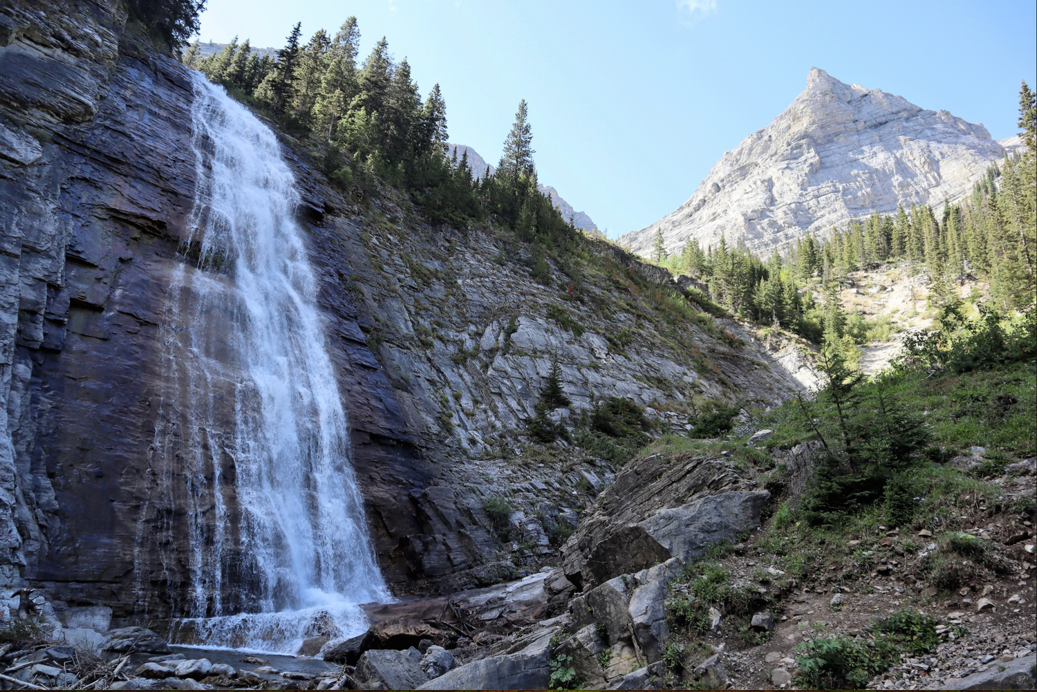 Ribbon Falls waterfall in Kananaskis on the left side of the frame with a mountain peak in the right side of the frame