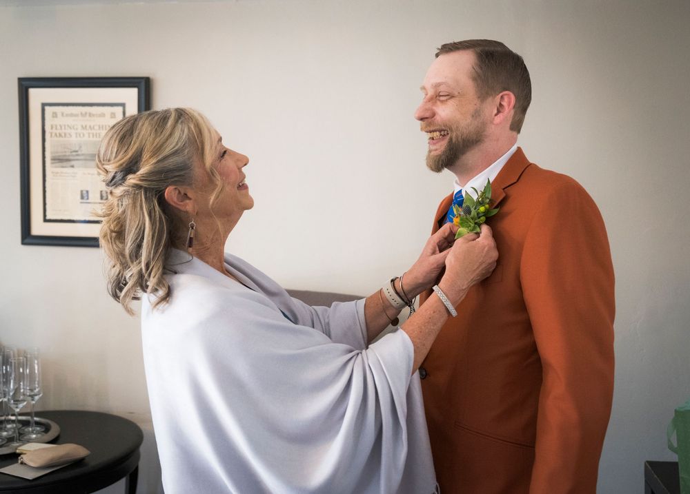 Wedding party members adjust formal attire and boutonnières while getting ready for the ceremony.
