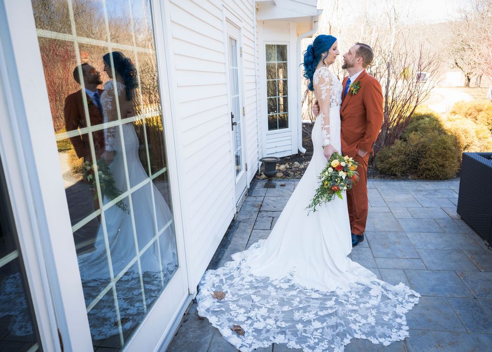 Elegant white wedding dress train flows across outdoor stone patio on a sunny winter day.