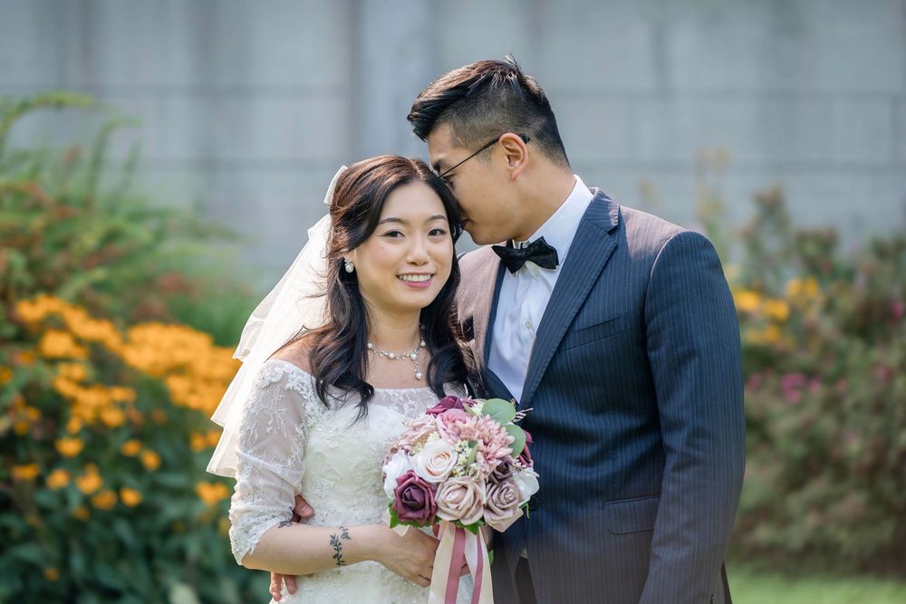Elegant wedding portrait with orange flowers blooming in background.