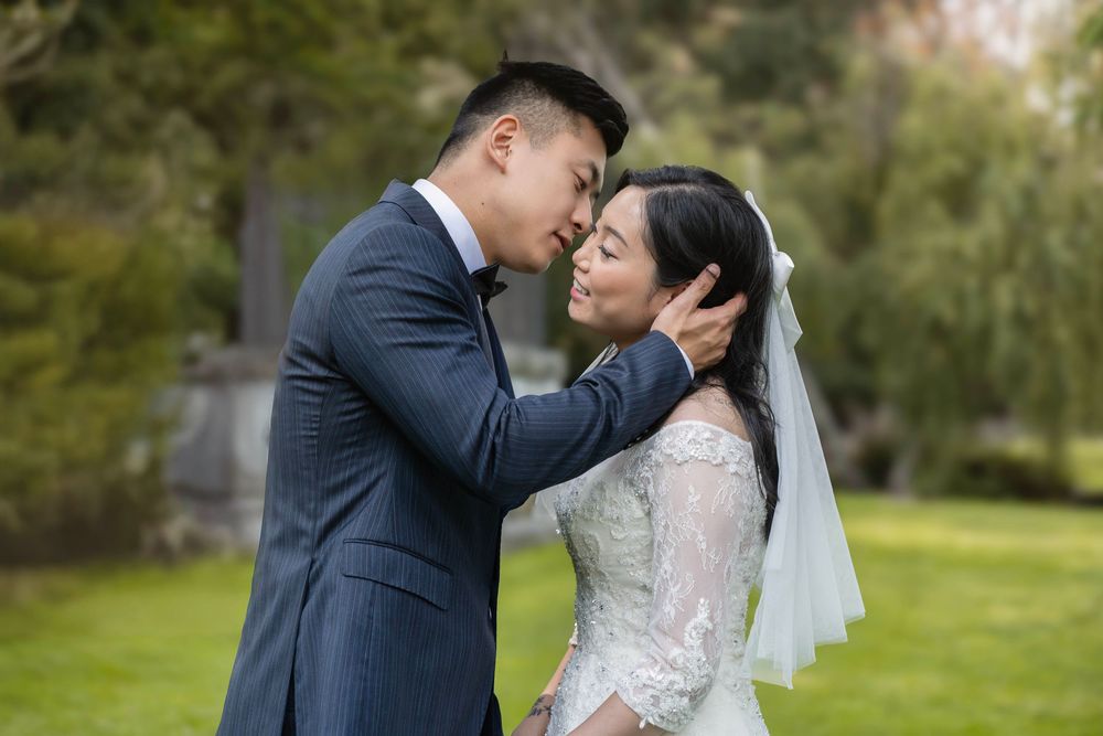 Intimate wedding portrait showing tender moment between couple in outdoor garden setting.