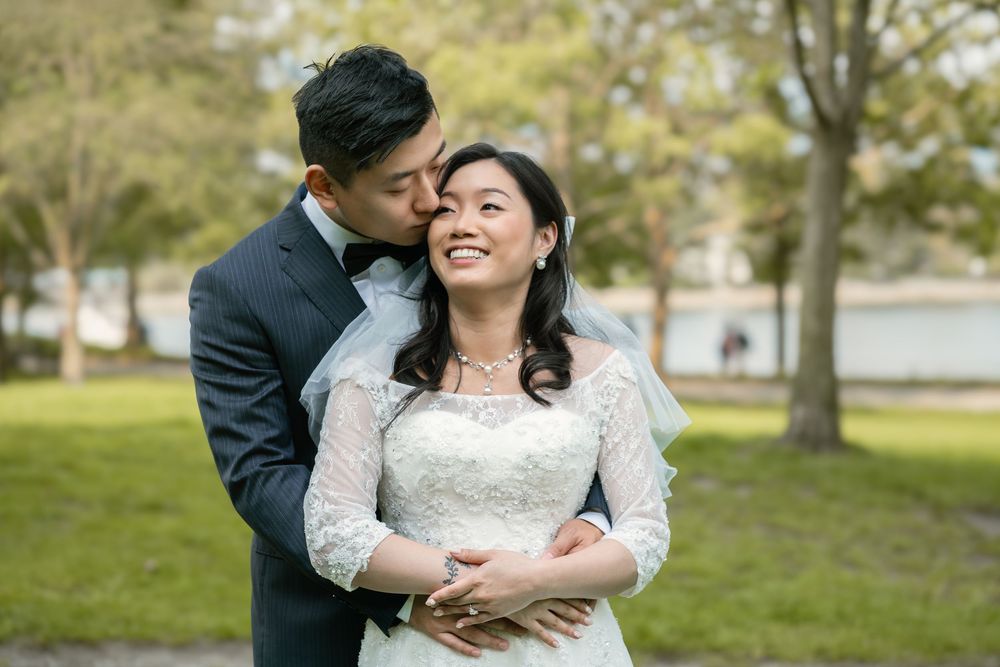 Romantic wedding portrait with couple embracing in outdoor park setting.