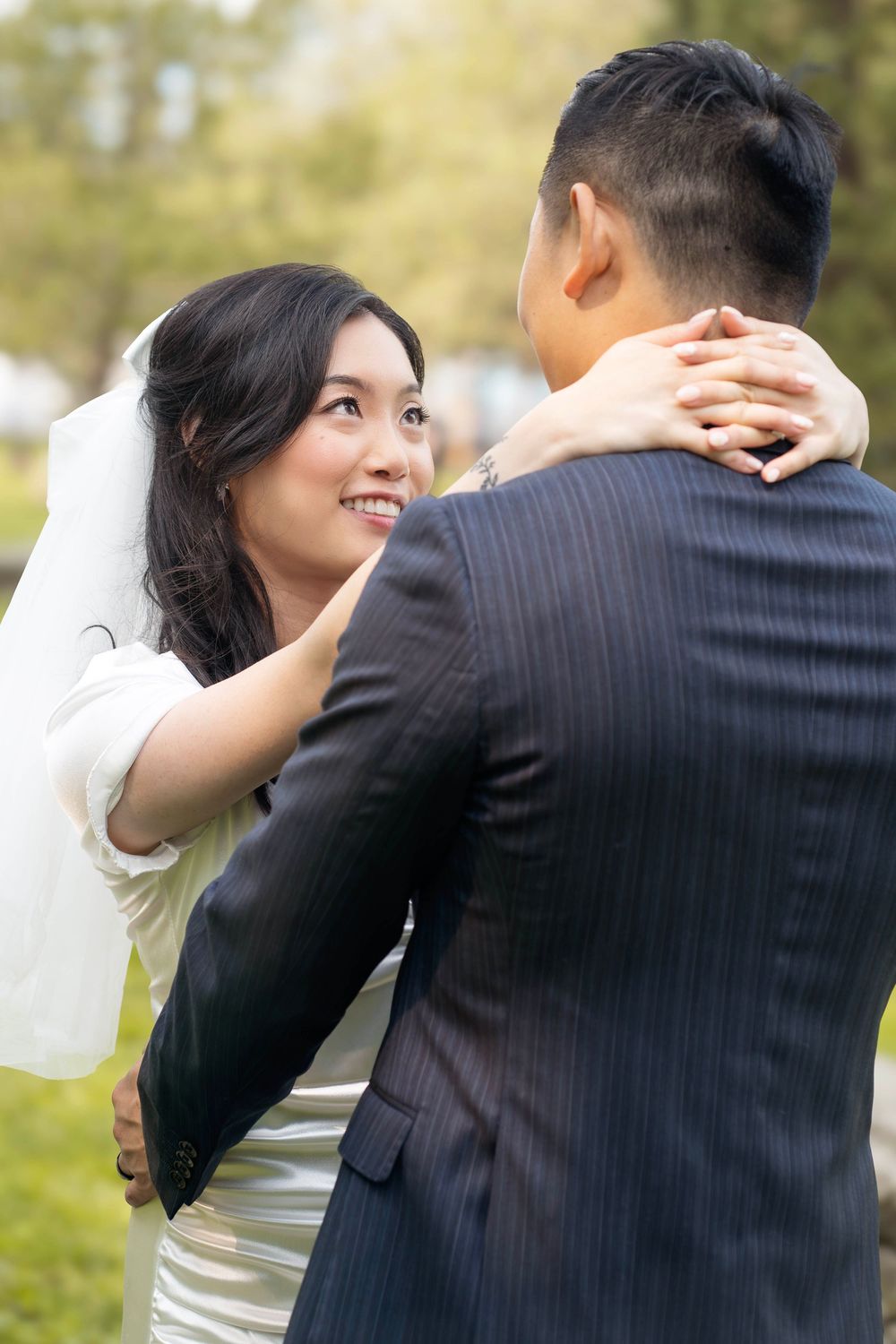 Candid wedding moment captured as couple embraces in garden setting.