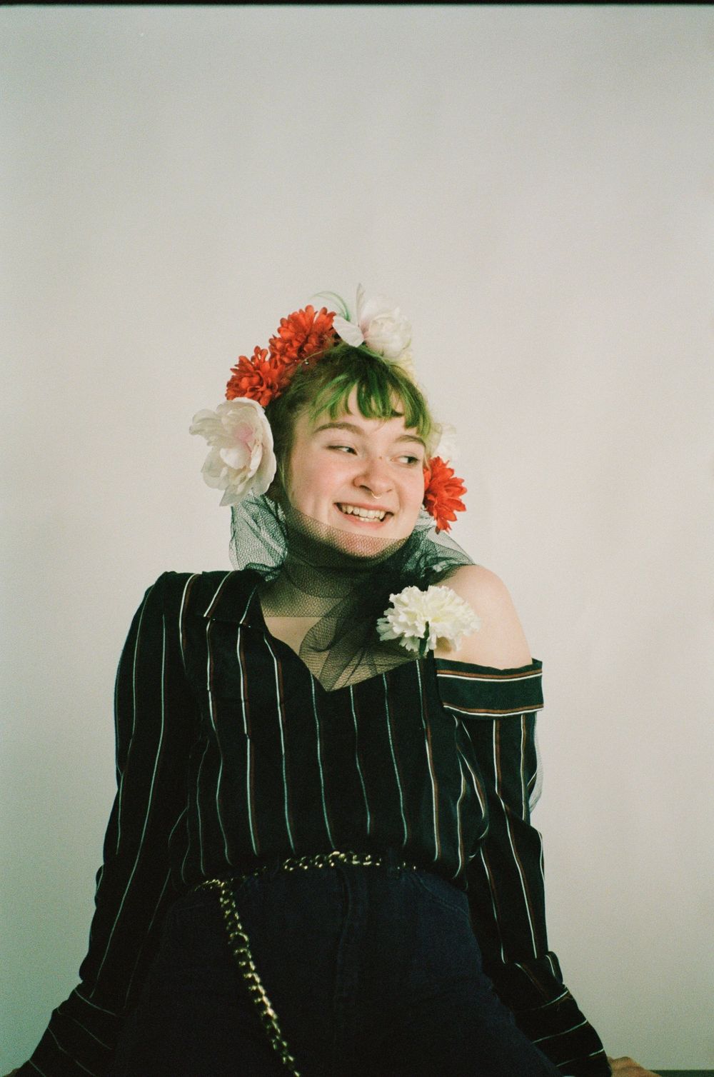 Studio editorial portraits with floral accessories, green hair, and pinstriped clothing against white backdrop.
