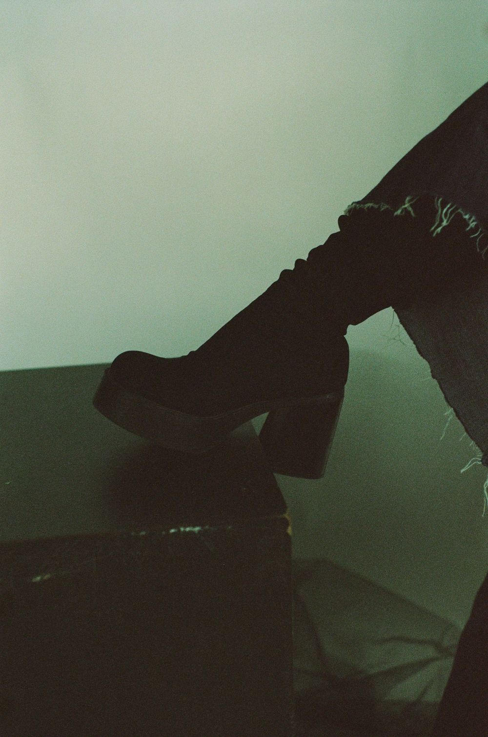 Dark editorial silhouetted shapes creating abstract forms against green tinted background.