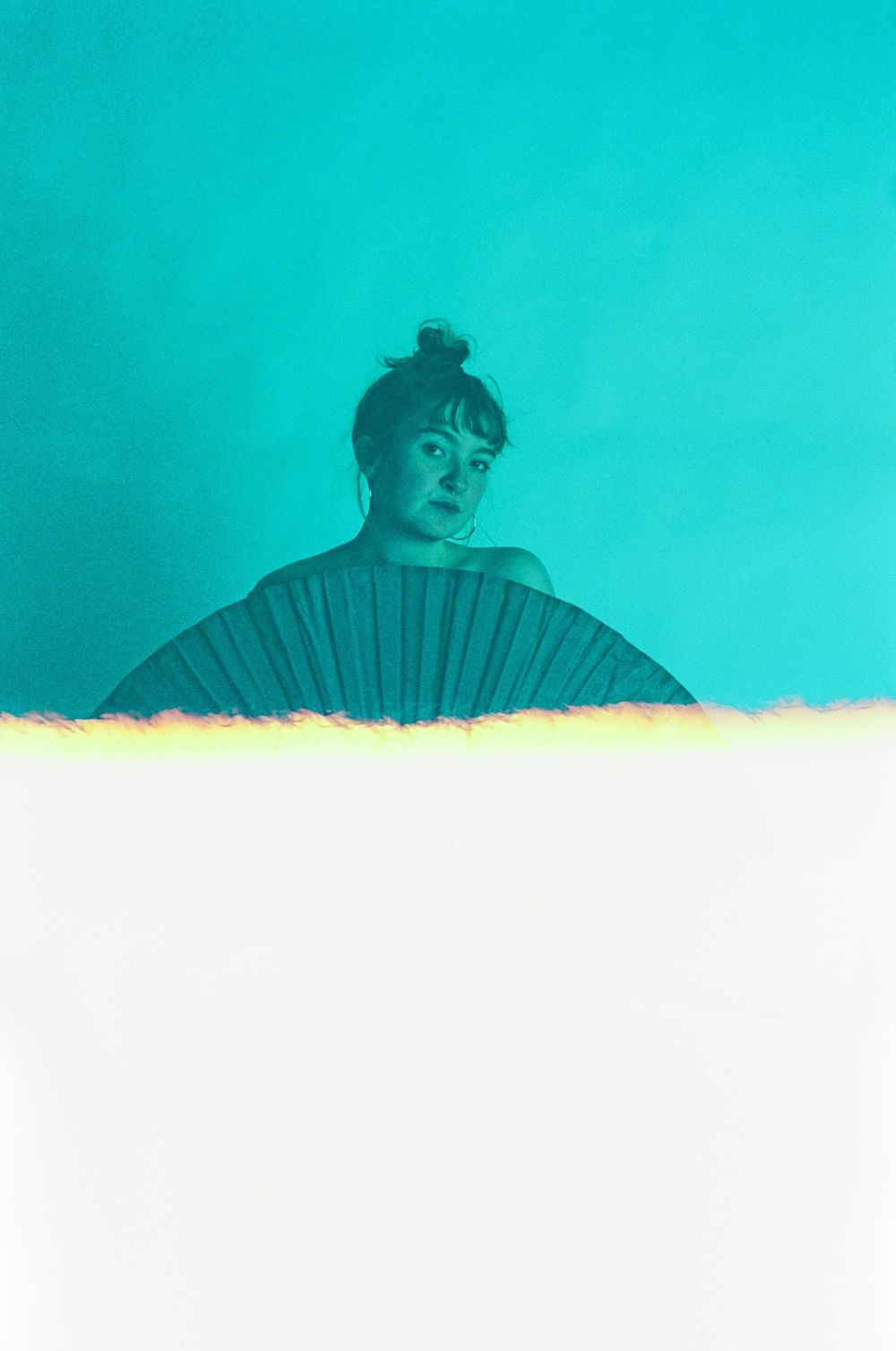 Artistic editorial portrait series with turquoise background and dramatic fan prop.