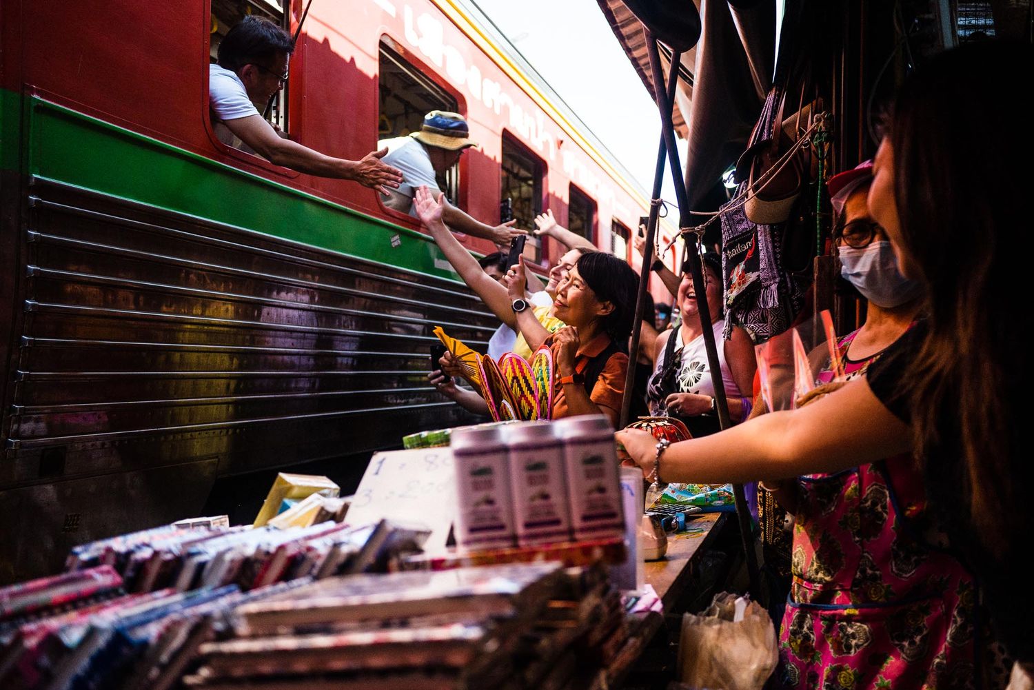 Crowded train platform in Asia with passengers boarding a red commuter train during rush hour.
