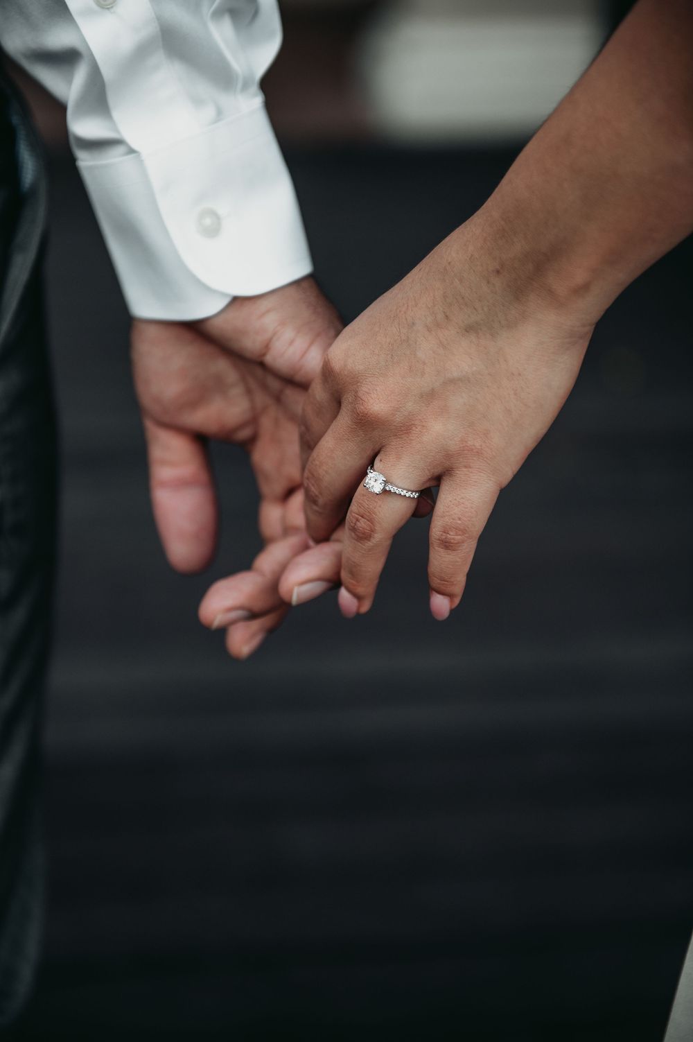 Close-up sequence of hands holding and displaying an engagement ring against a dark background.