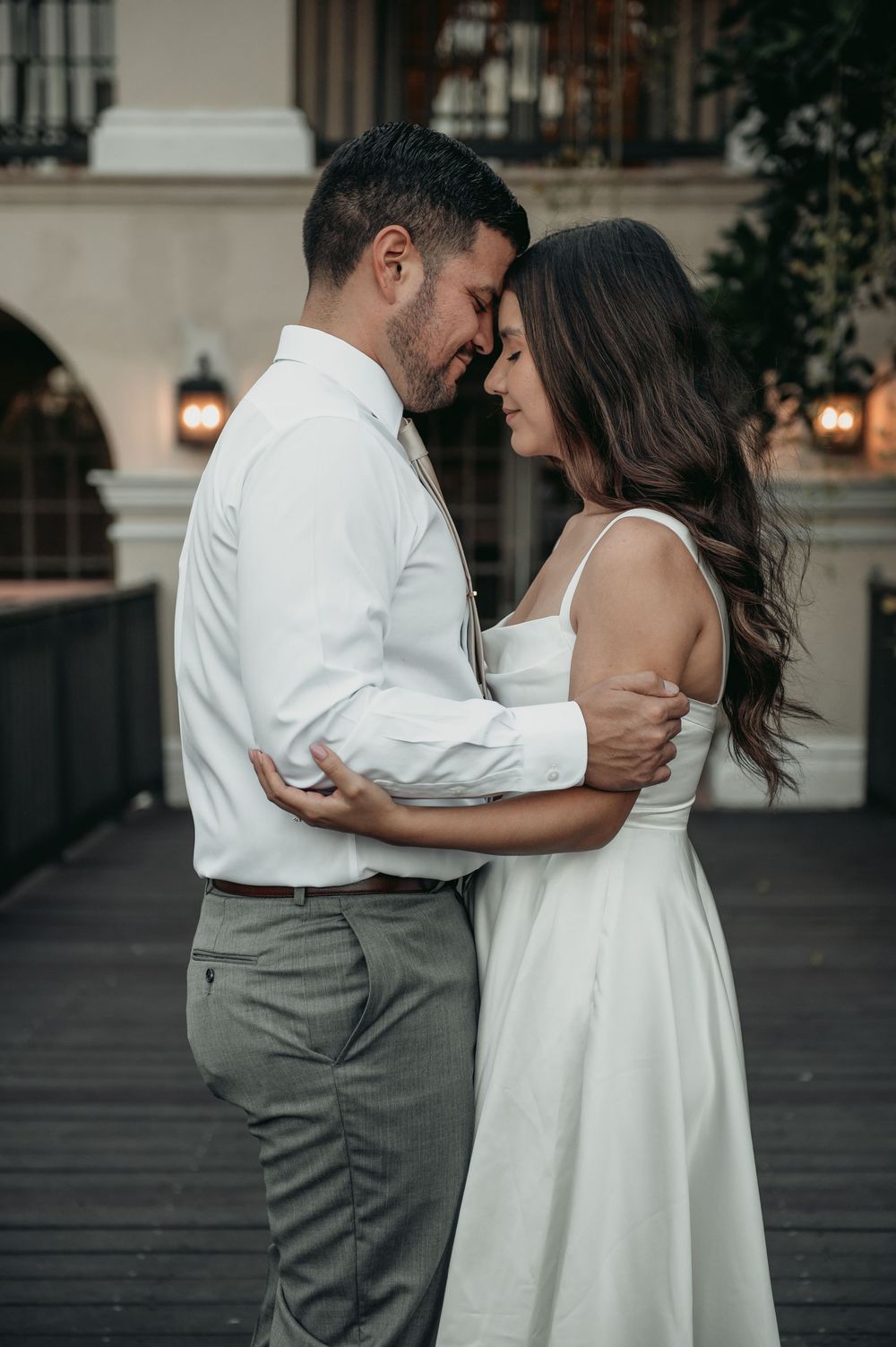 Romantic couple in white and gray attire share intimate moments in a series of outdoor portraits at dusk.