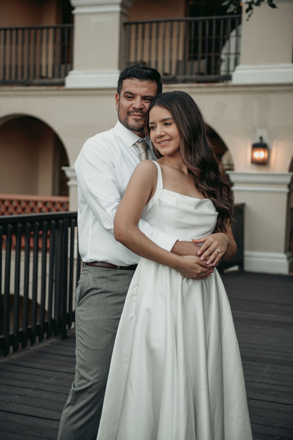 Couple embraces and laughs together during romantic outdoor photo session on a patio.