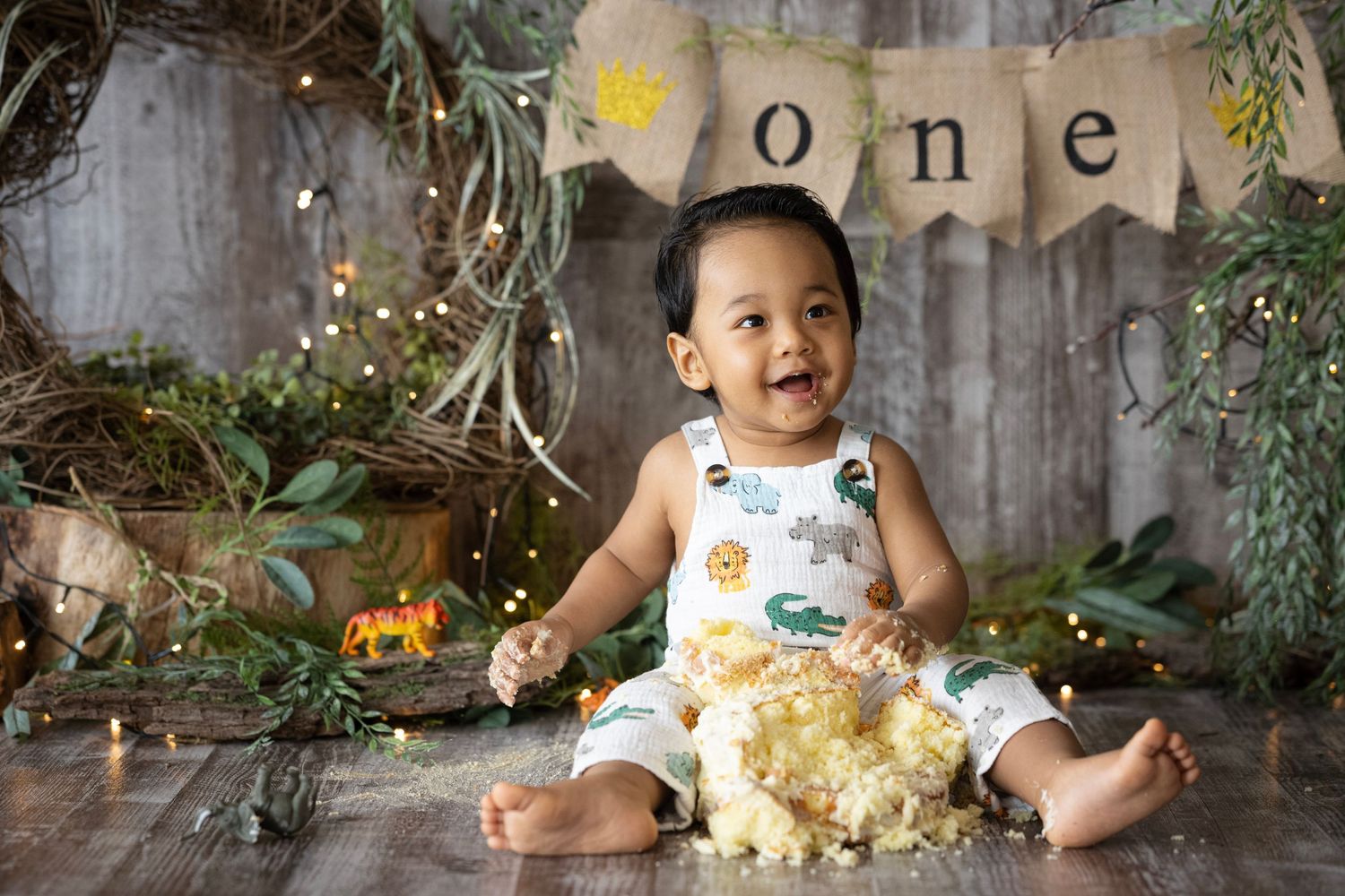 First birthday celebration setup with rustic banner and decorative lights against wooden backdrop.