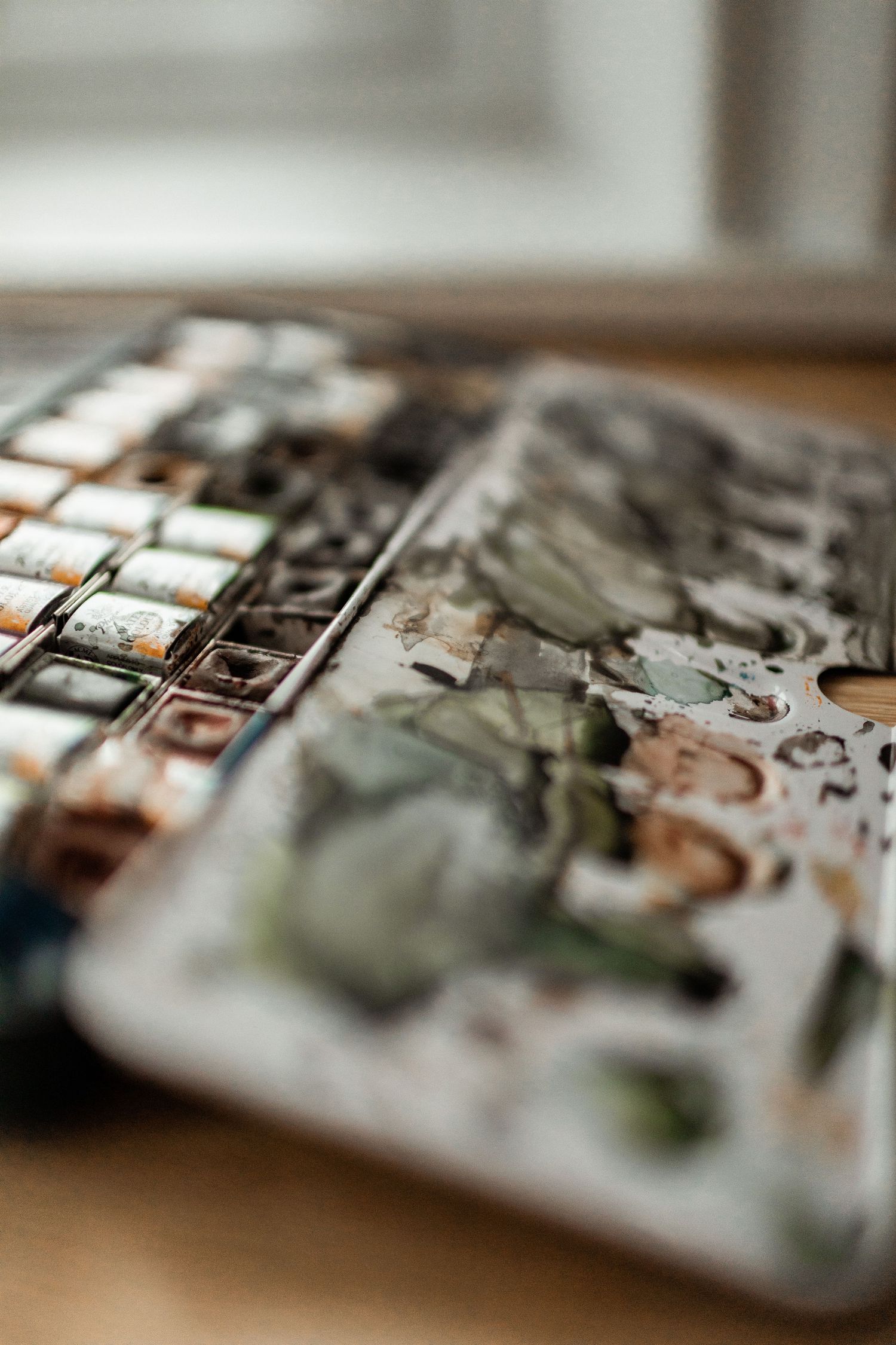 Close-up of a watercolor palette with mixed paint colors.