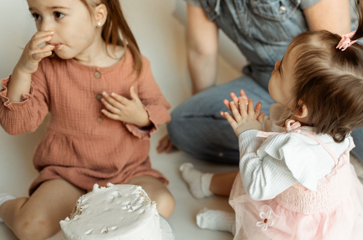 Young children playing and interacting while sitting on a light colored floor.