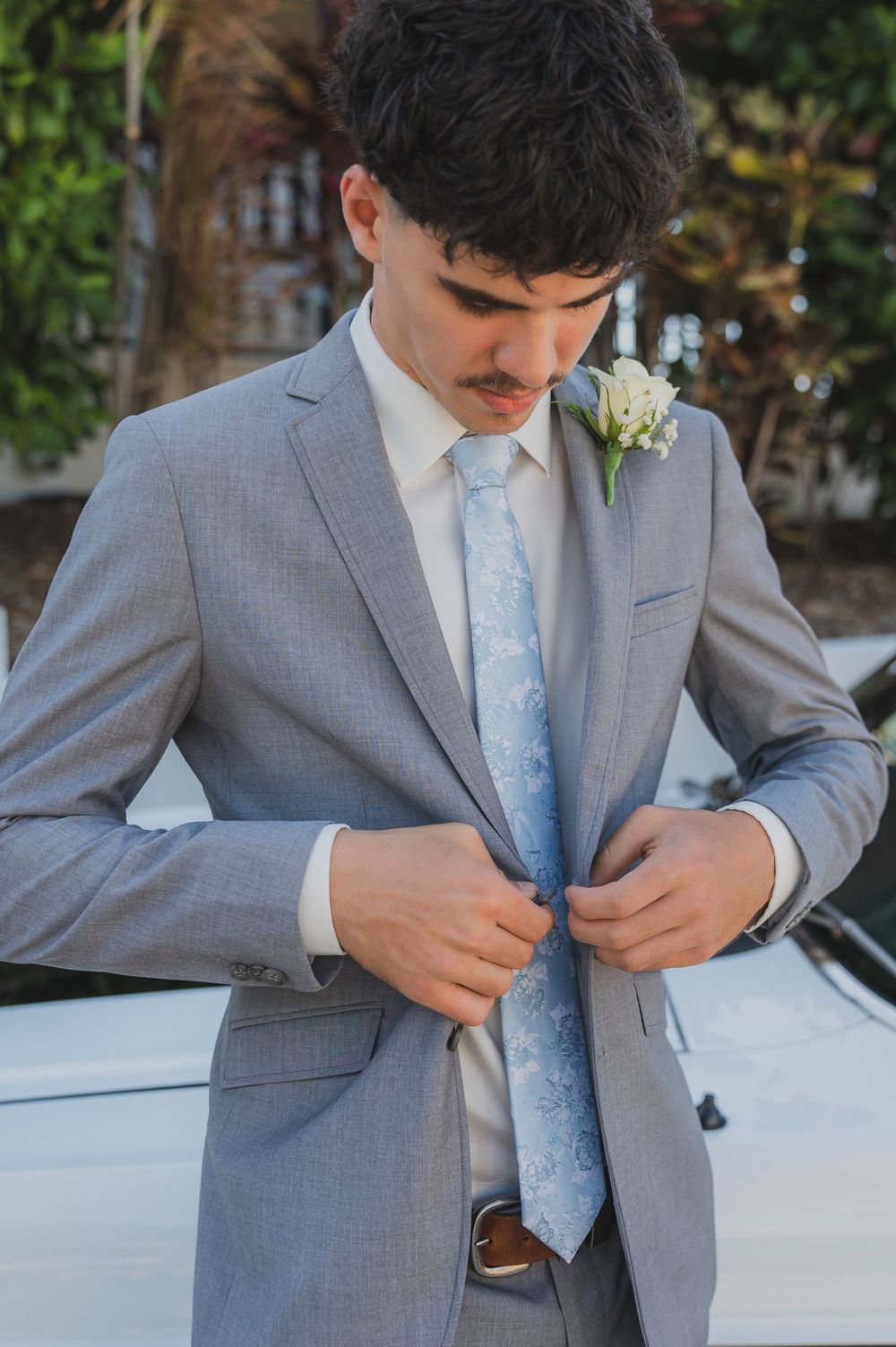 A person in a light gray suit adjusts their powder blue tie in a series of close-up photos.
