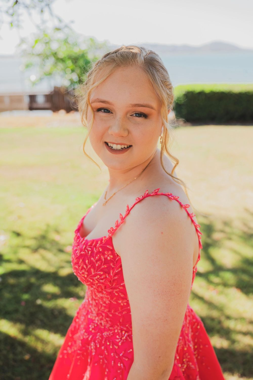 A series of joyful portraits in a bright outdoor setting featuring someone wearing a vibrant red lace dress.