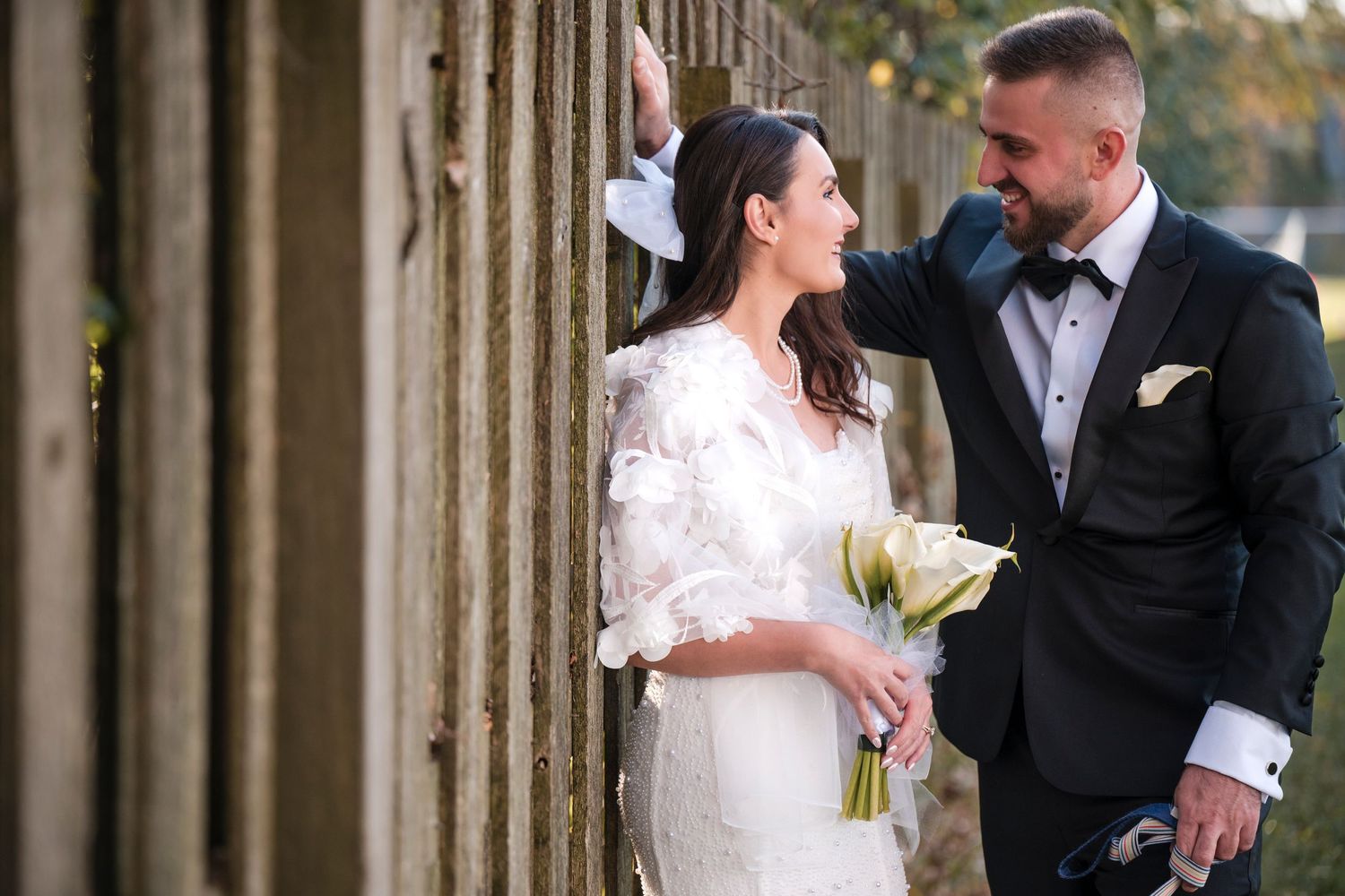 A bride and groom share joyful moments together during their wedding photoshoot in front of stone columns.