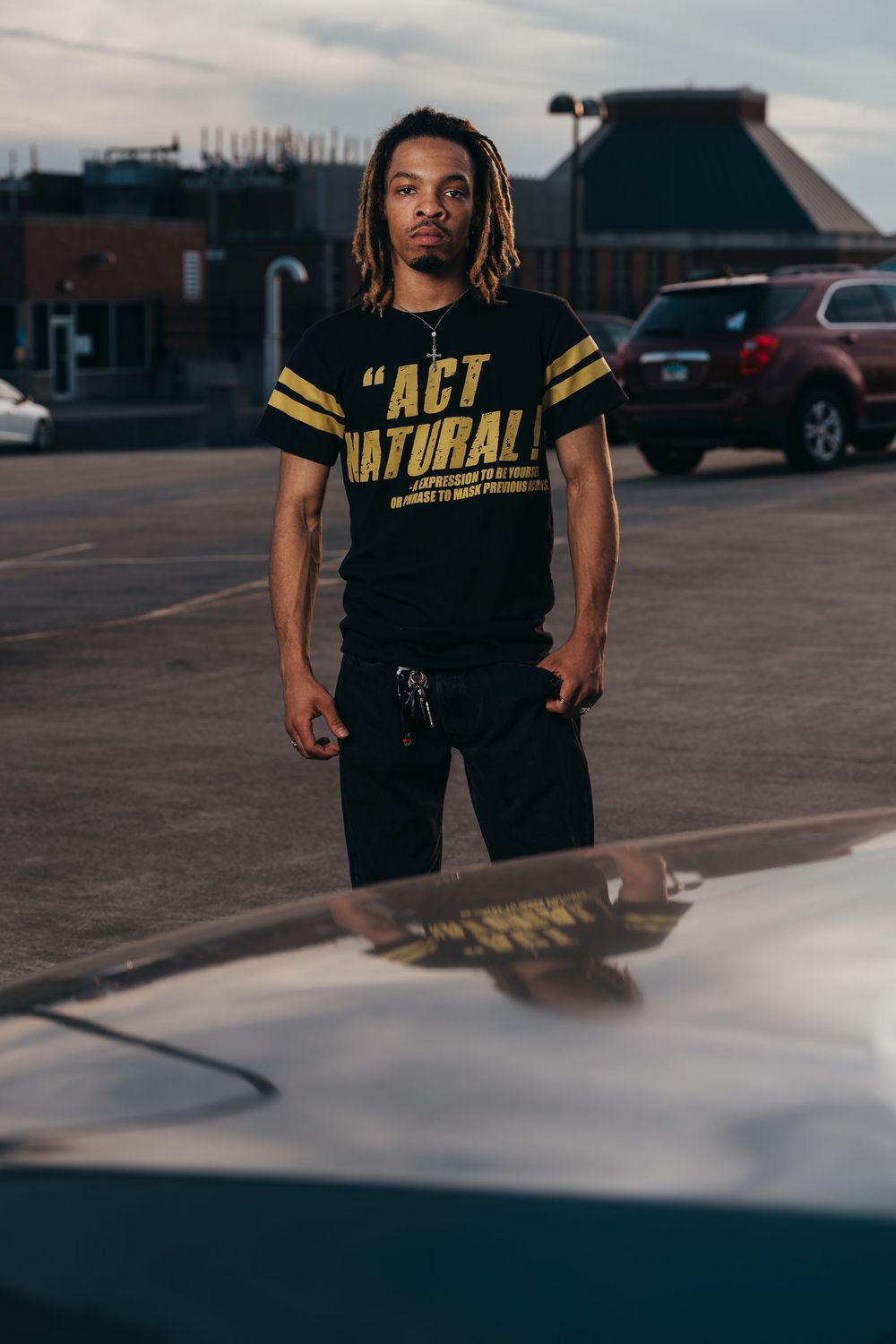 Person wearing black and yellow athletic clothing standing in an empty parking lot at dusk.