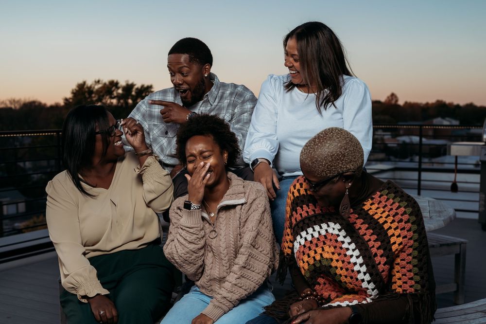 Group enjoying casual conversation on rooftop during sunset.