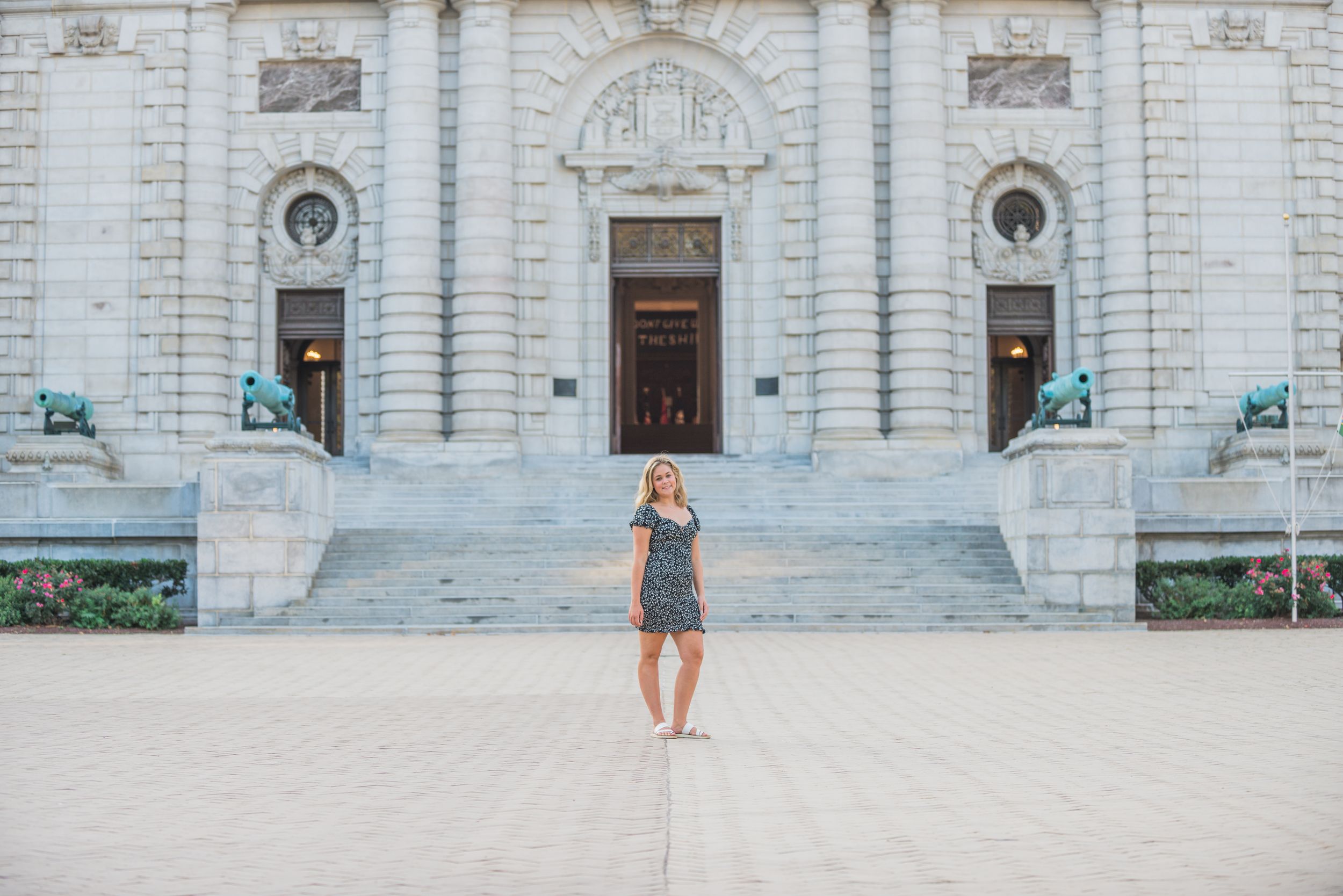 This senior is posing in front of a grand historic Naval Academy building with ornate architecture and stone steps.